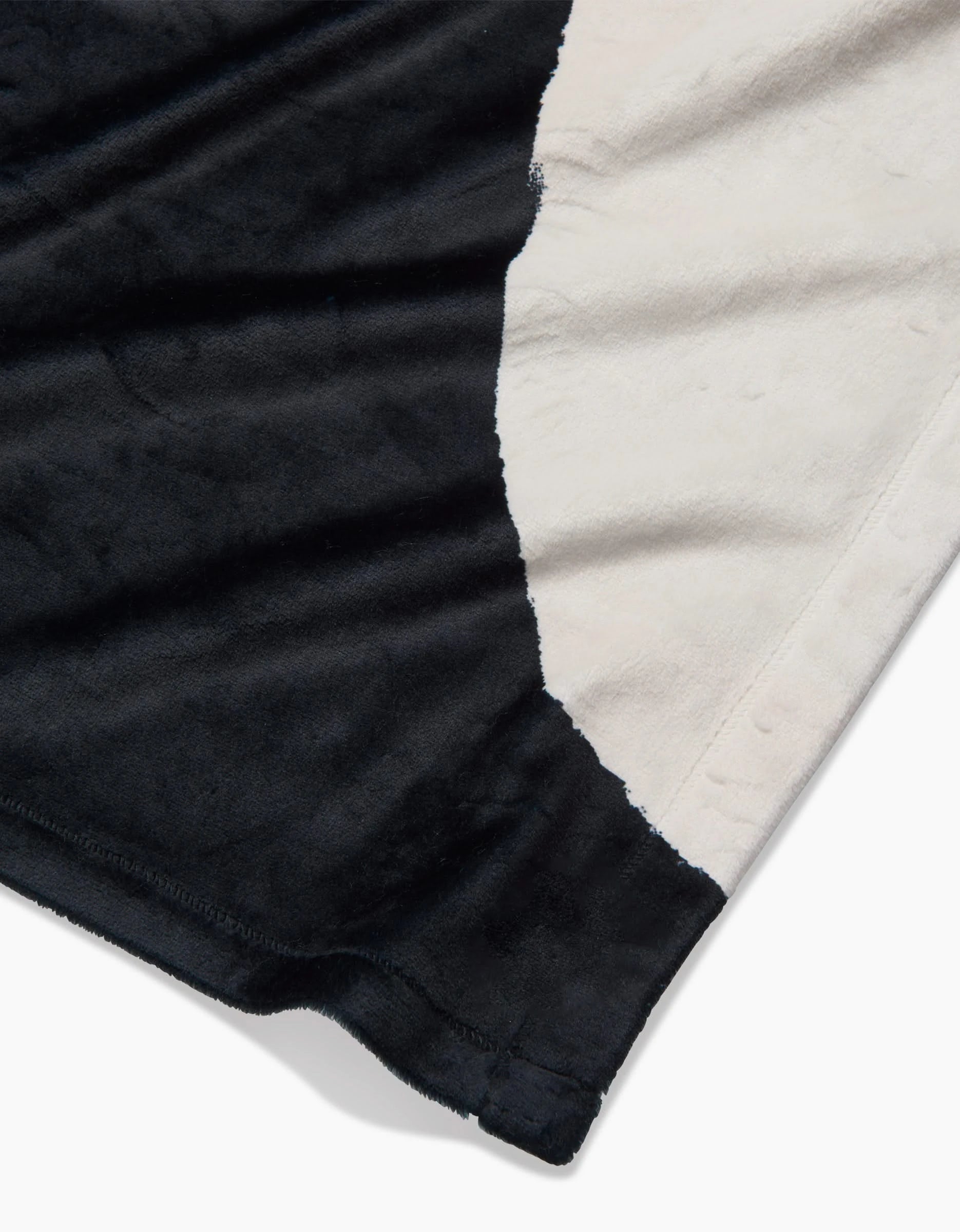 A close-up of Geometrys Lined Square showcases its soft, plush Butter Blanket fabric in a black and white pattern; edge stitching highlights its silky softness.