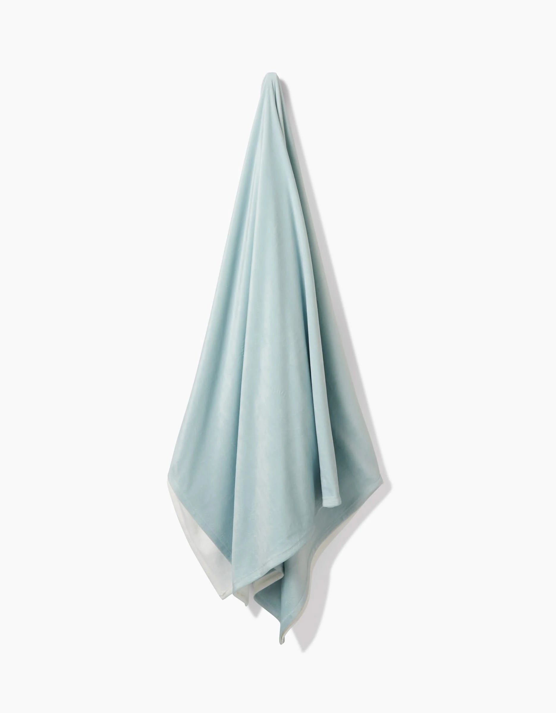 The GEOMETRY Mint Drift towel, made from post-consumer recycled materials, hangs from a single point against a white background, offering silky softness with every touch.