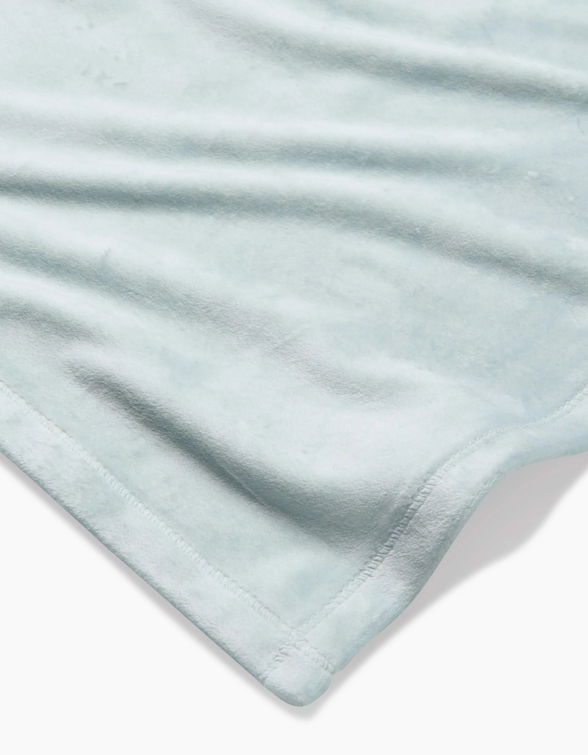 A close-up of the GEOMETRY Mint Drift Butter Blanket, made from post-consumer recycled materials with silky softness and neatly stitched edges, laid flat on a white background.
