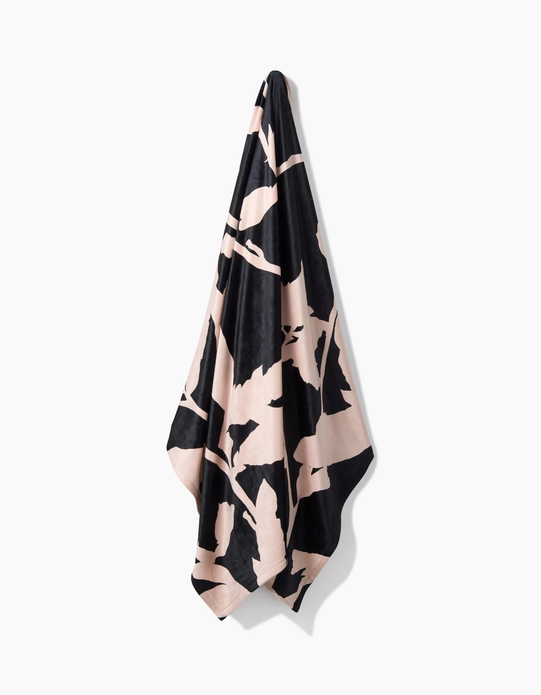 Pam, a black and beige patterned towel by Geometry made from recycled materials, hangs on a hook against a white background.