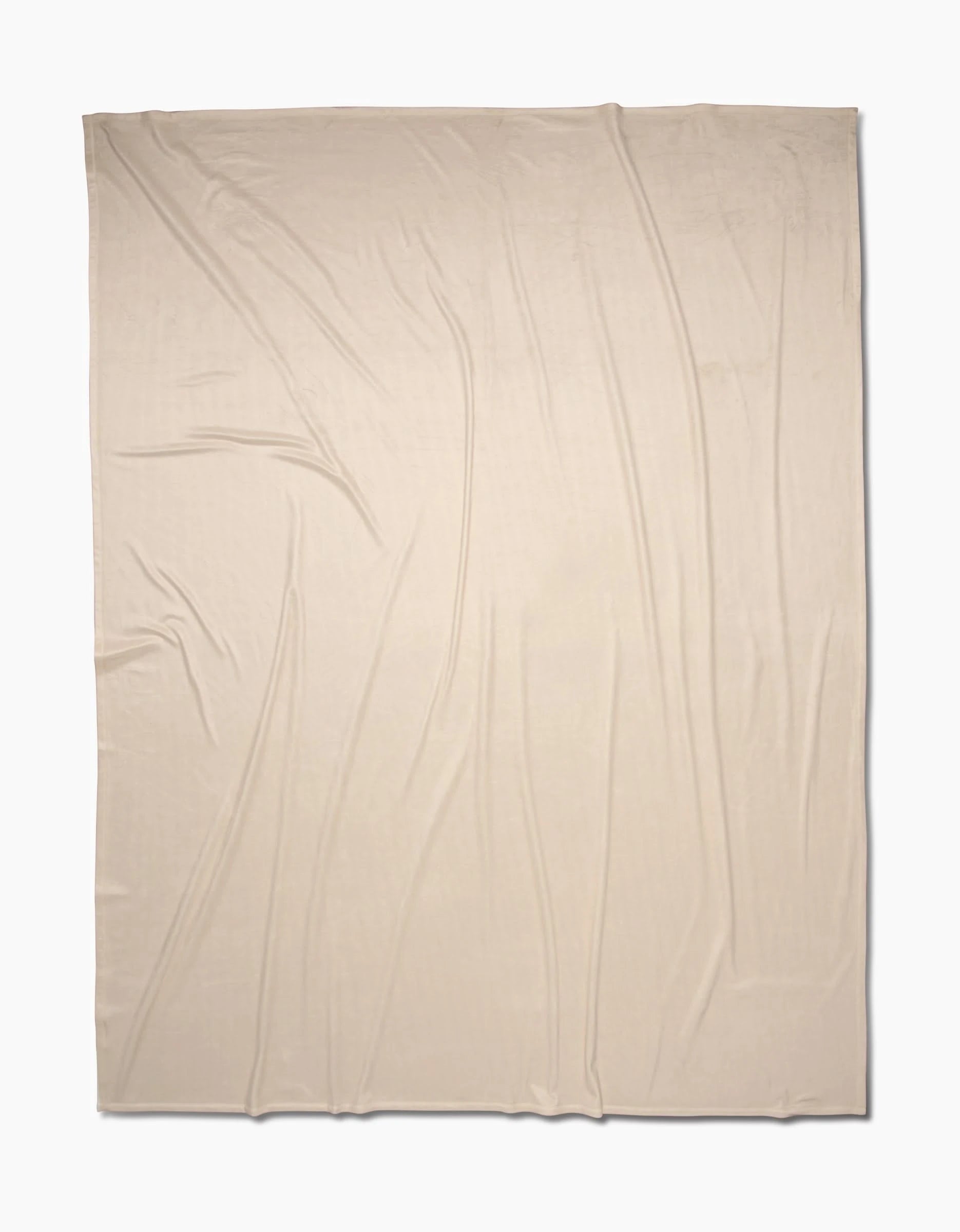 A light beige, rectangular Soft Glow blanket by GEOMETRY is displayed flat with gentle, natural folds. Made from eco-friendly recycled materials, the fabric rests on a plain white background.