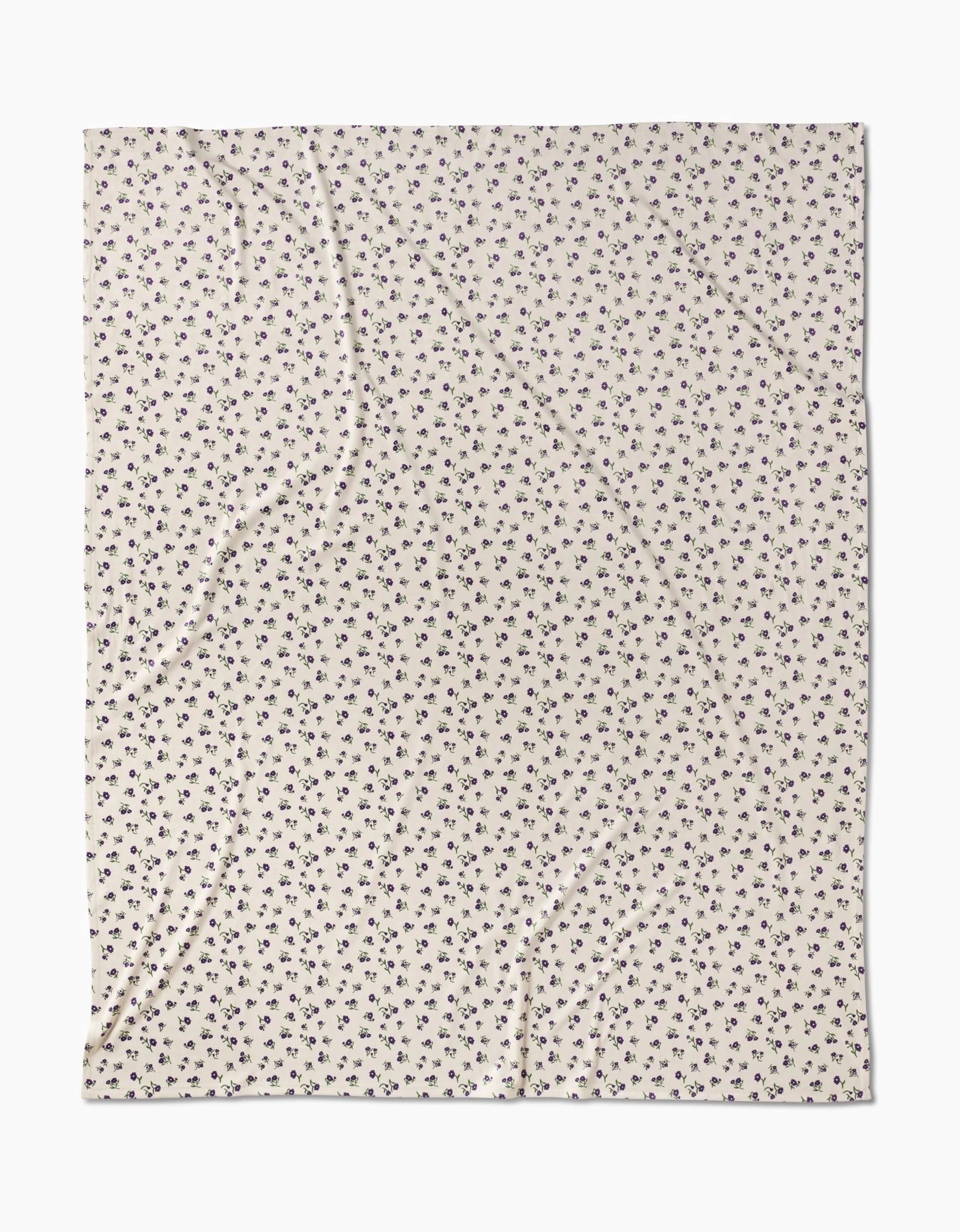 The Violet Sound fabric by Geometry features a cream base with a repeating small black floral pattern, made from recycled materials and displayed flat to reveal subtle wrinkles and folds.