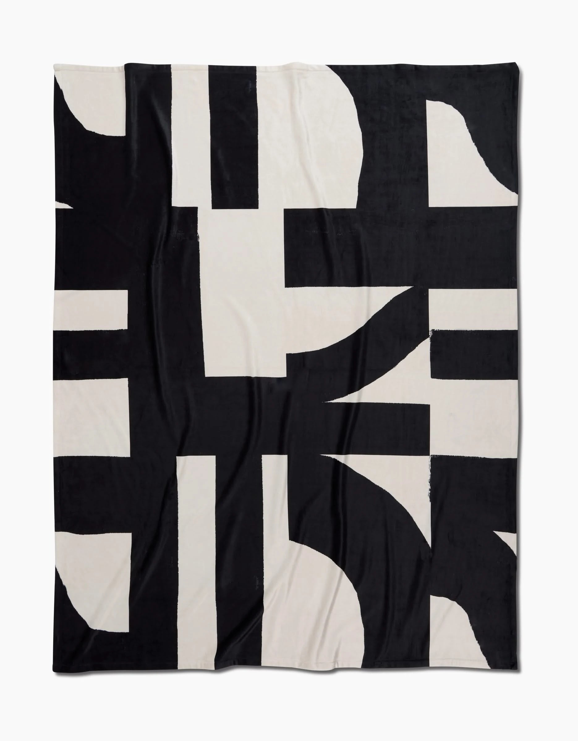 Geometry’s Lined Square Butter Blanket features a bold black and off-white abstract geometric pattern with intersecting shapes and thick lines. Made from post-consumer recycled materials, it offers silky softness and sustainable comfort.
