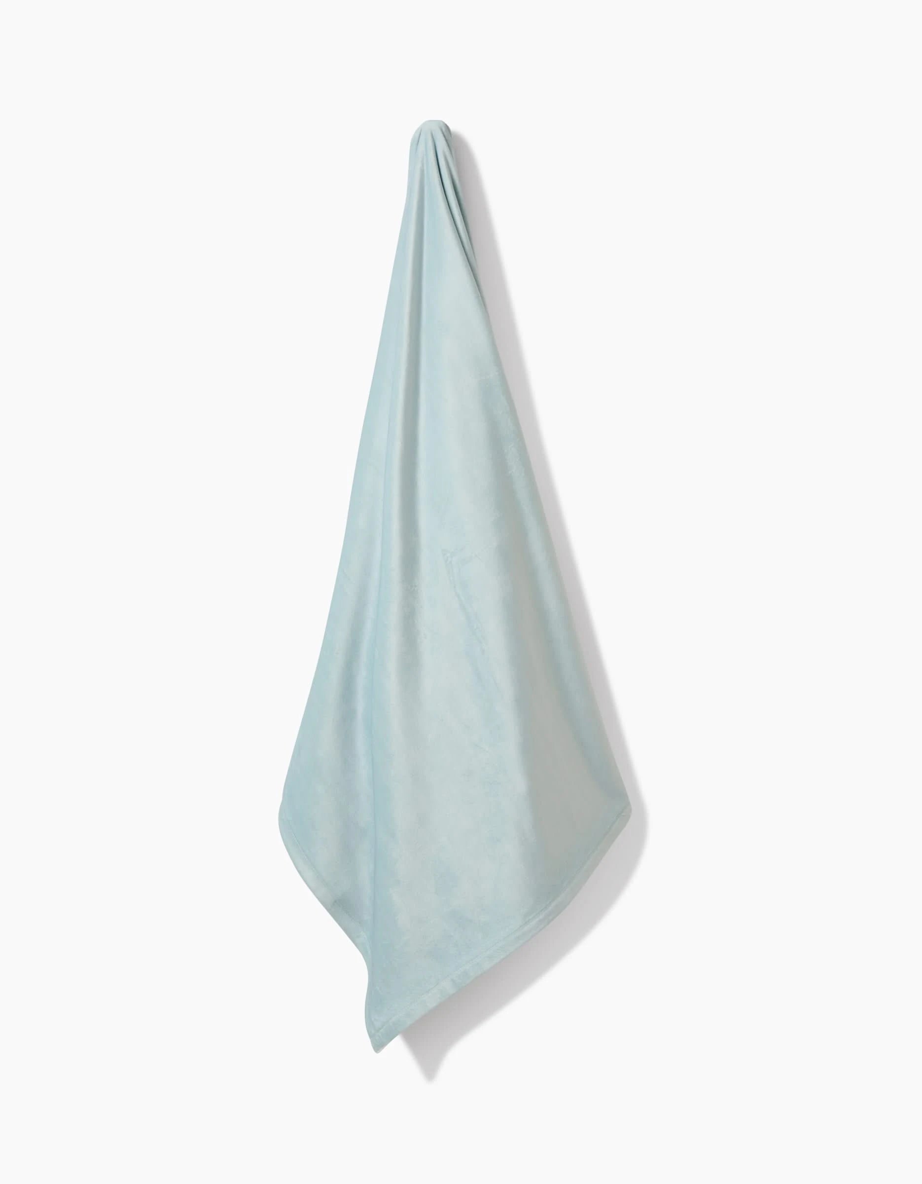 A Mint Drift towel by GEOMETRY, made from post-consumer recycled materials, hangs from a single point against a plain white background, draping softly in gentle folds.