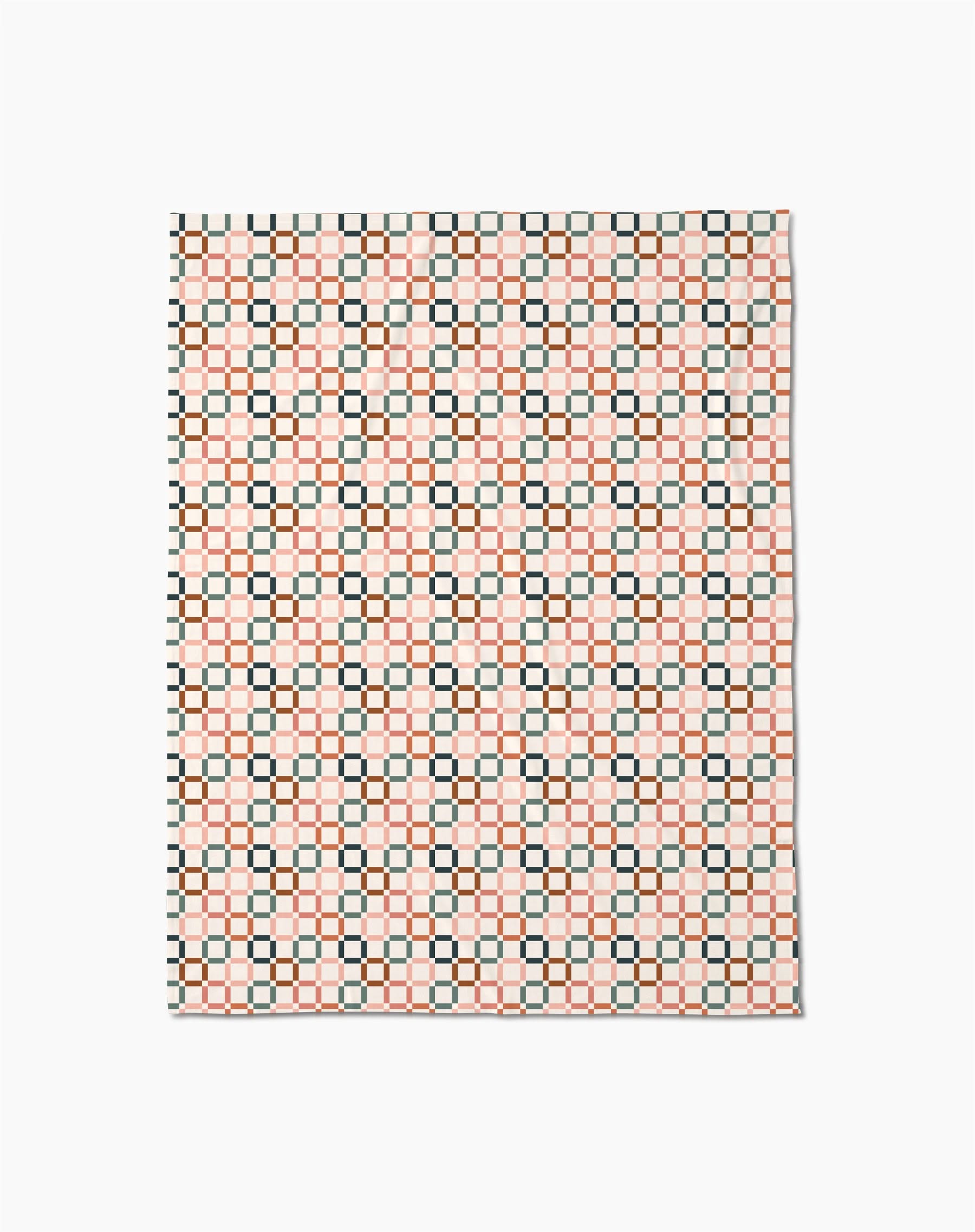 The Russet Crossroads Butter Blanket by Charlie Rowan Designs features a geometric grid of black, red, and cream squares on white, crafted from recycled materials for an eco-friendly touch.