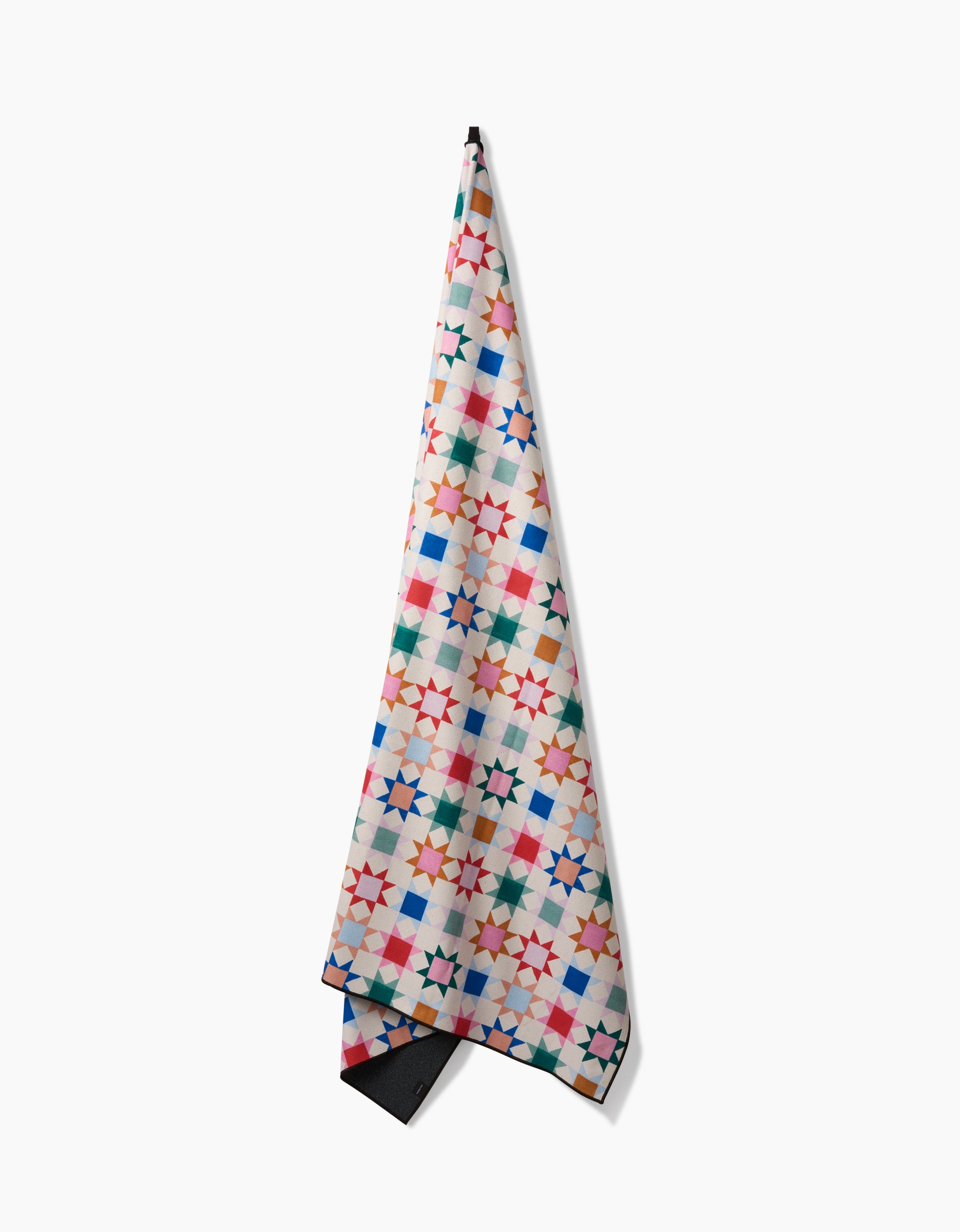 Patchwork Picnic by Brittany Jepsen is a quick-drying towel featuring a vibrant geometric star design in red, blue, green, orange, and pink on white, displayed against a white background.