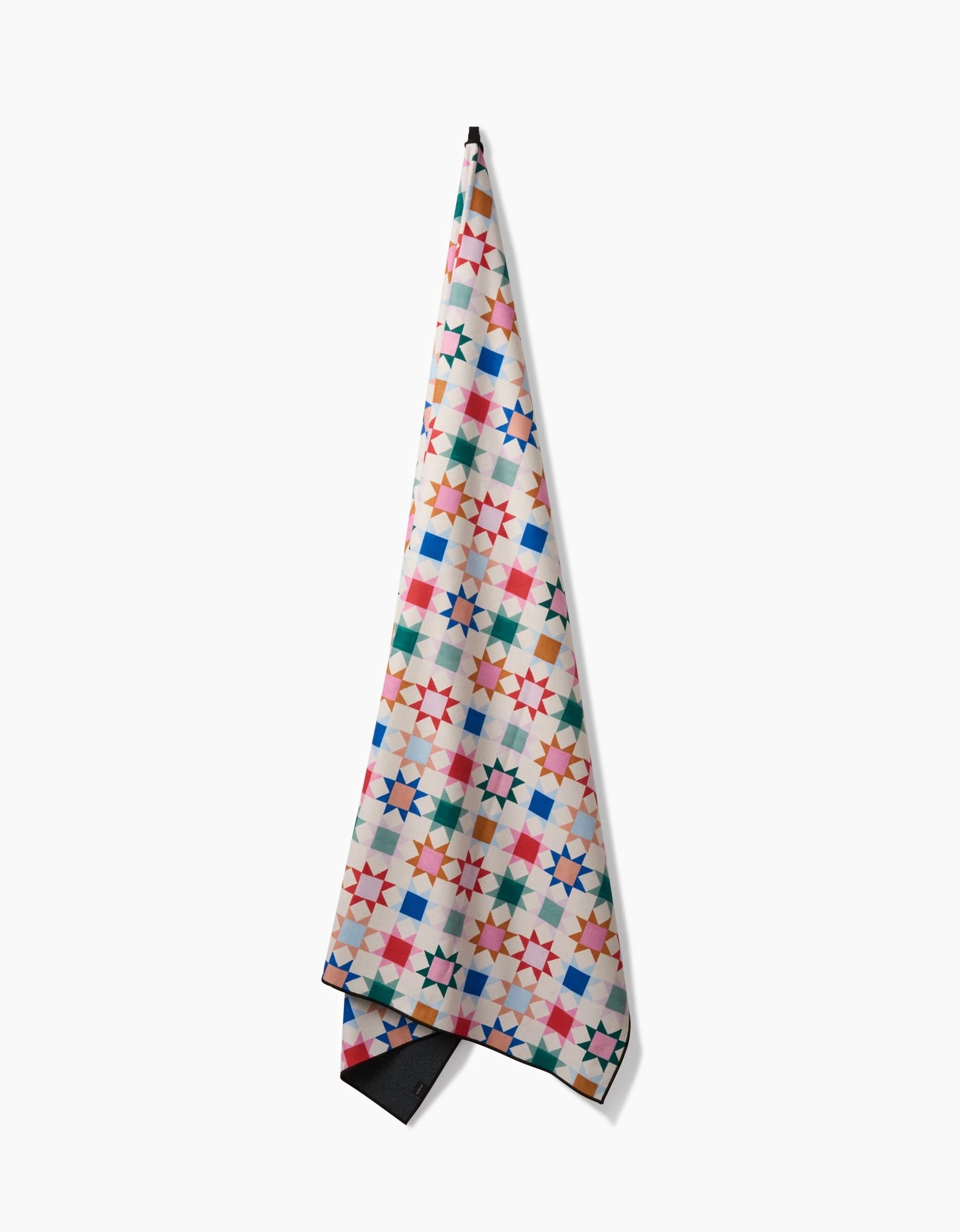 Patchwork Picnic by Brittany Jepsen is a quick-drying towel featuring a vibrant geometric star design in red, blue, green, orange, and pink on white, displayed against a white background.
