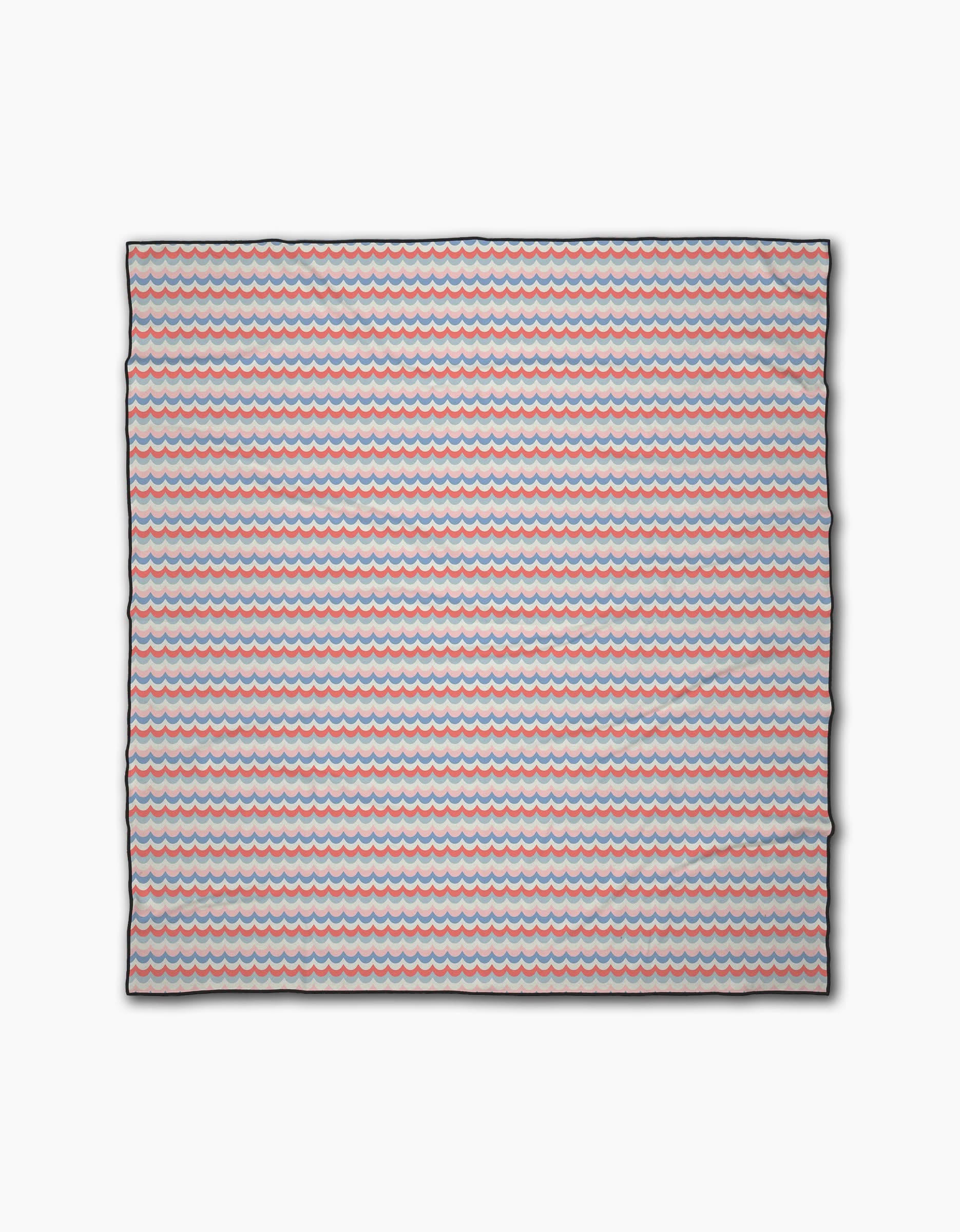 The Geometry Scallop Stripes is a square beach blanket made from recycled materials, featuring small red, blue, and white wavy stripes on a light background.
