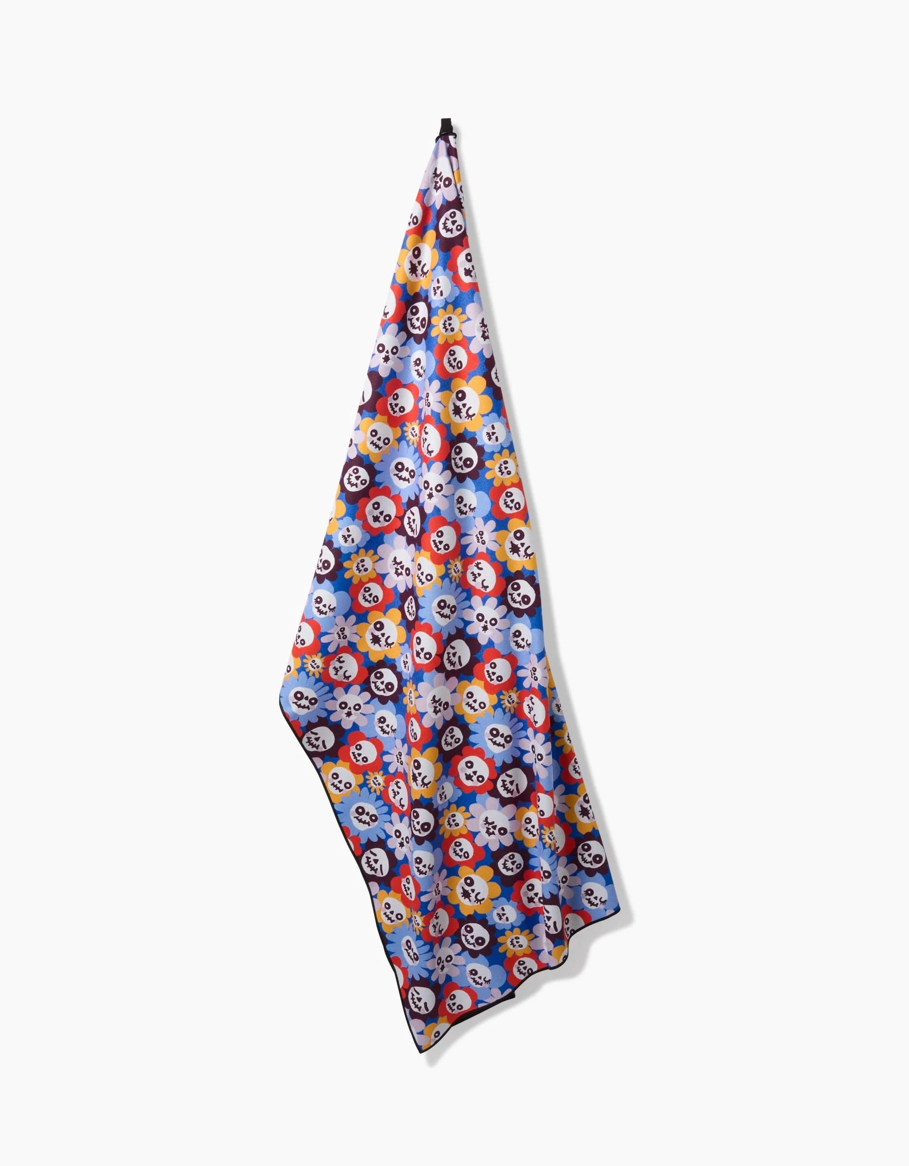 The So Lazo Spooky Bouquet towel, featuring a vibrant cartoon skull pattern, hangs from a single hook against a white background.