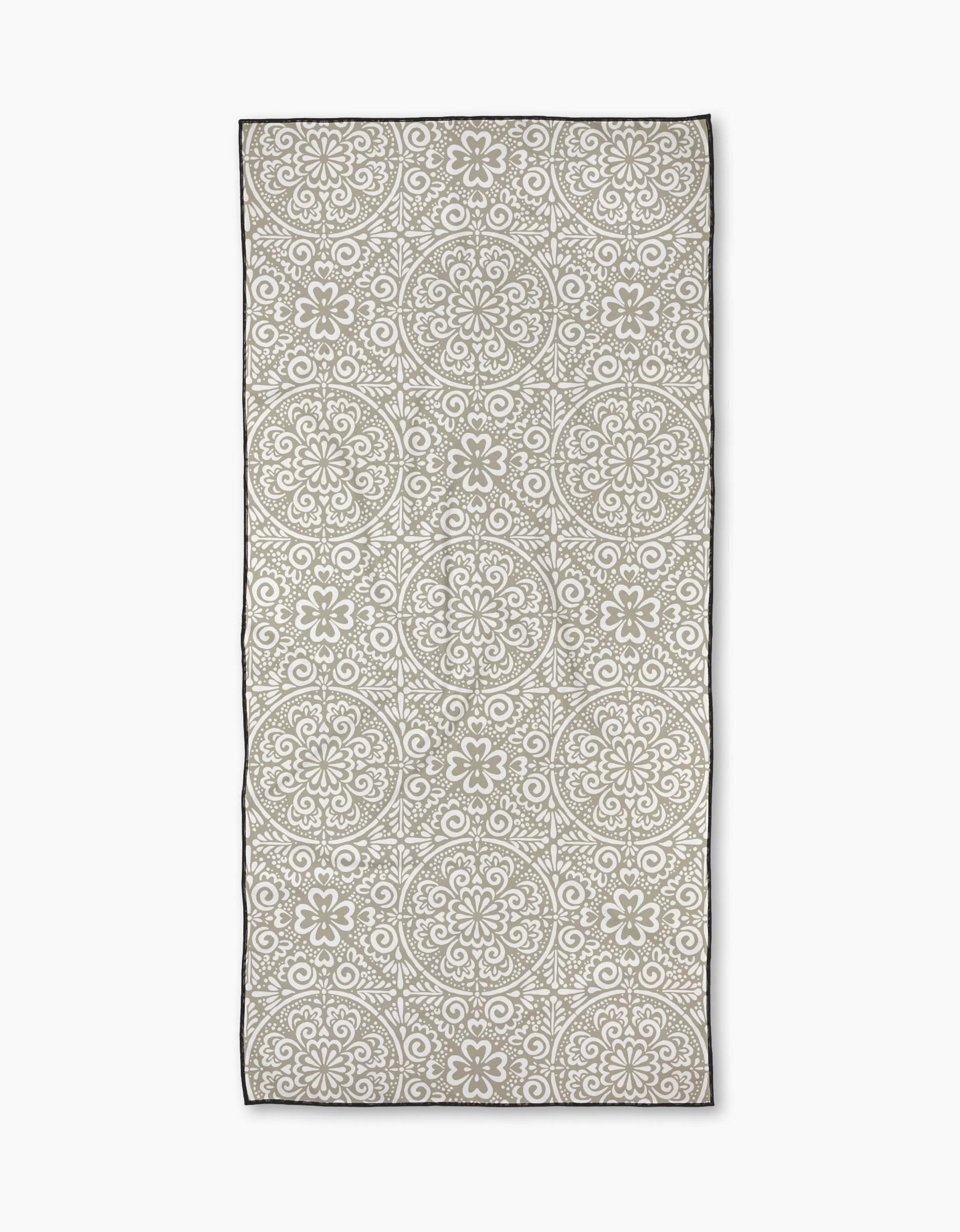 The Kris Ruff Boho Medallion is a rectangular micro-loop beach towel with a light gray background, white mandala pattern, and black border. Made from quick-drying recycled materials for eco-friendly comfort.
