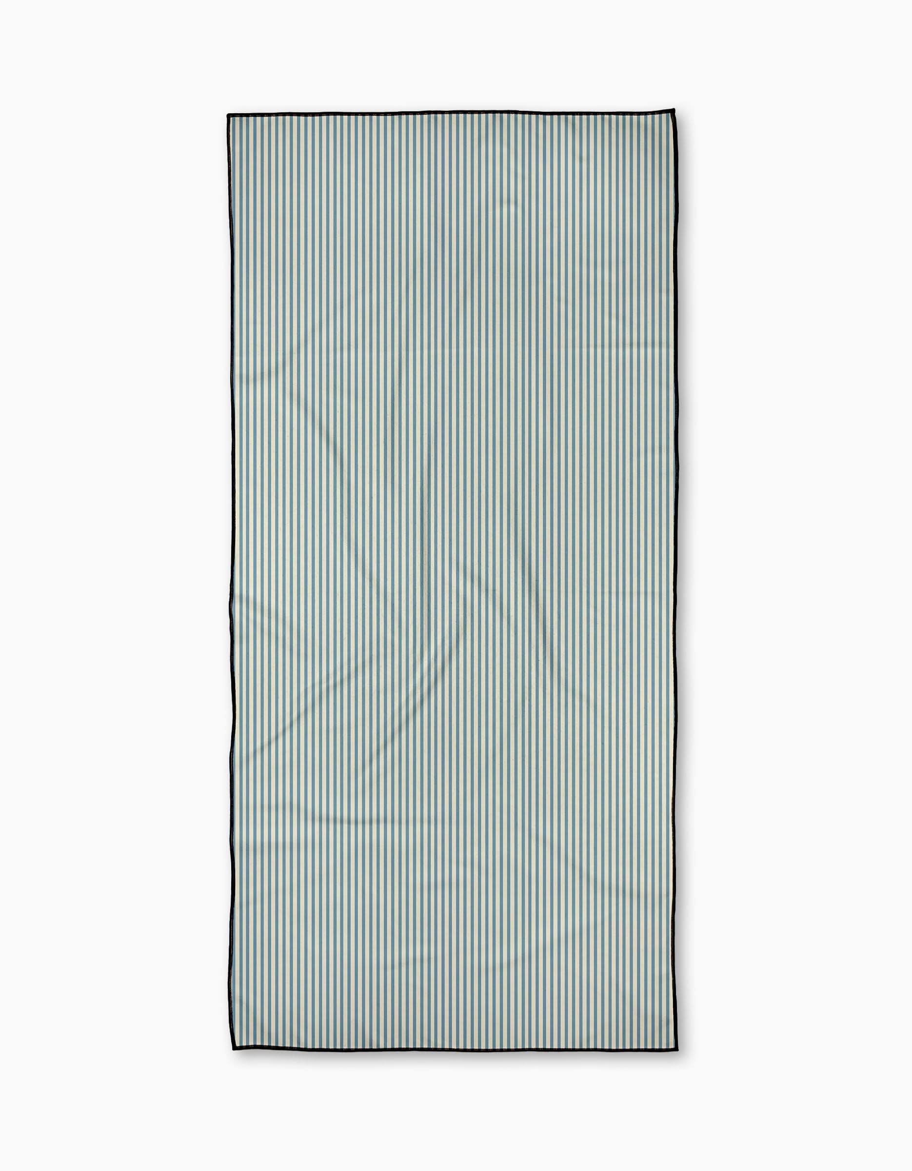 The Clean Slate beach towel by Susan Heid is rectangular and quick-drying, featuring thin, evenly spaced vertical blue and white stripes with a dark border, shown on a plain white background.