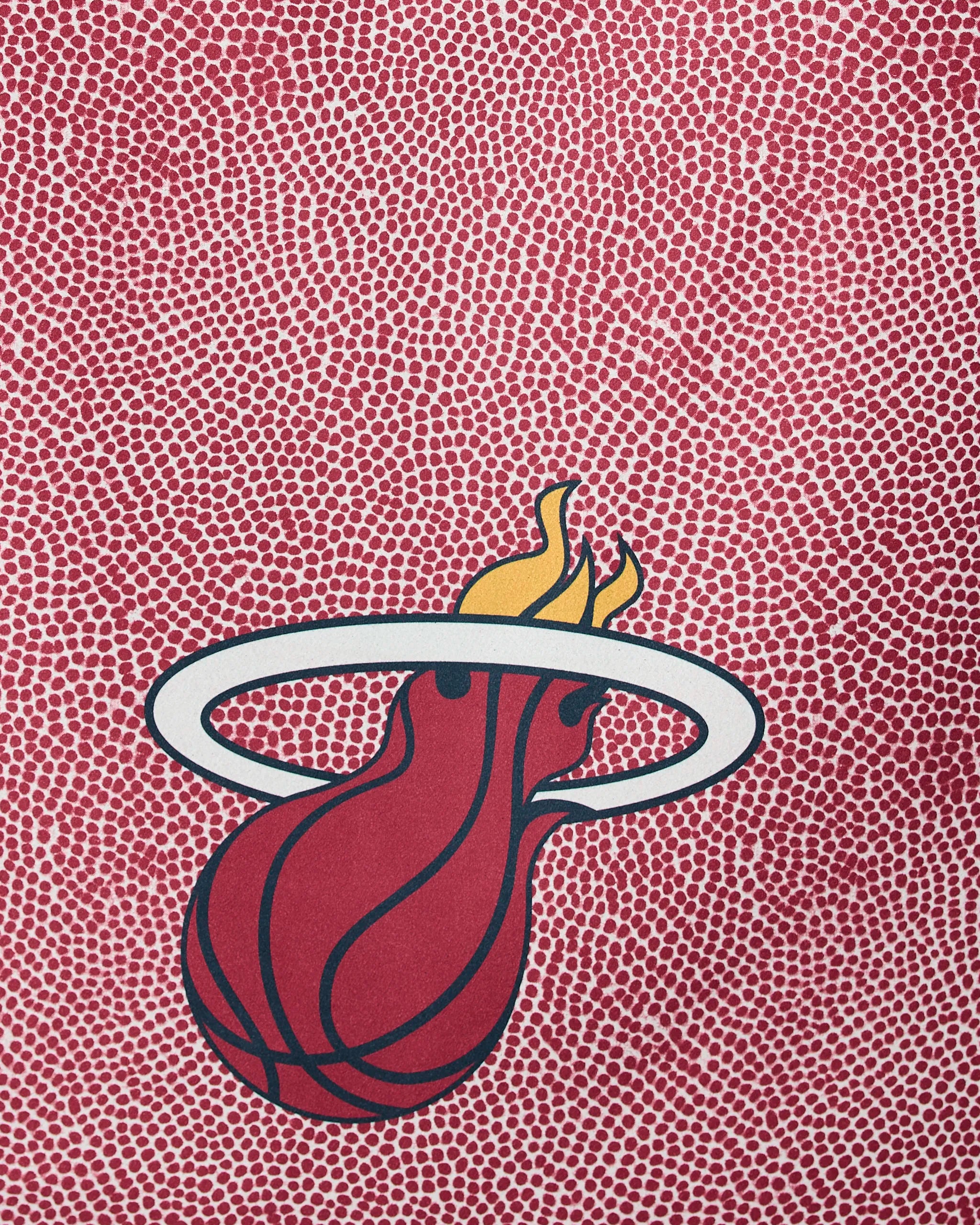 The Geometry Heat Grip showcases the Miami Heat logo—a flaming basketball through a white hoop—on a textured red and white dotted background reminiscent of a basketball surface.