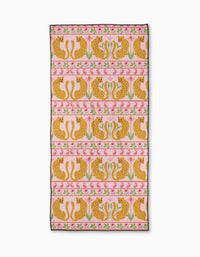 The Jungle Blooms Pink beach towel by Jasmine Blooms Designs is rectangular, quick-drying, and features a pink background with symmetrical rows of illustrated cheetahs and pink flowers in a decorative pattern.
