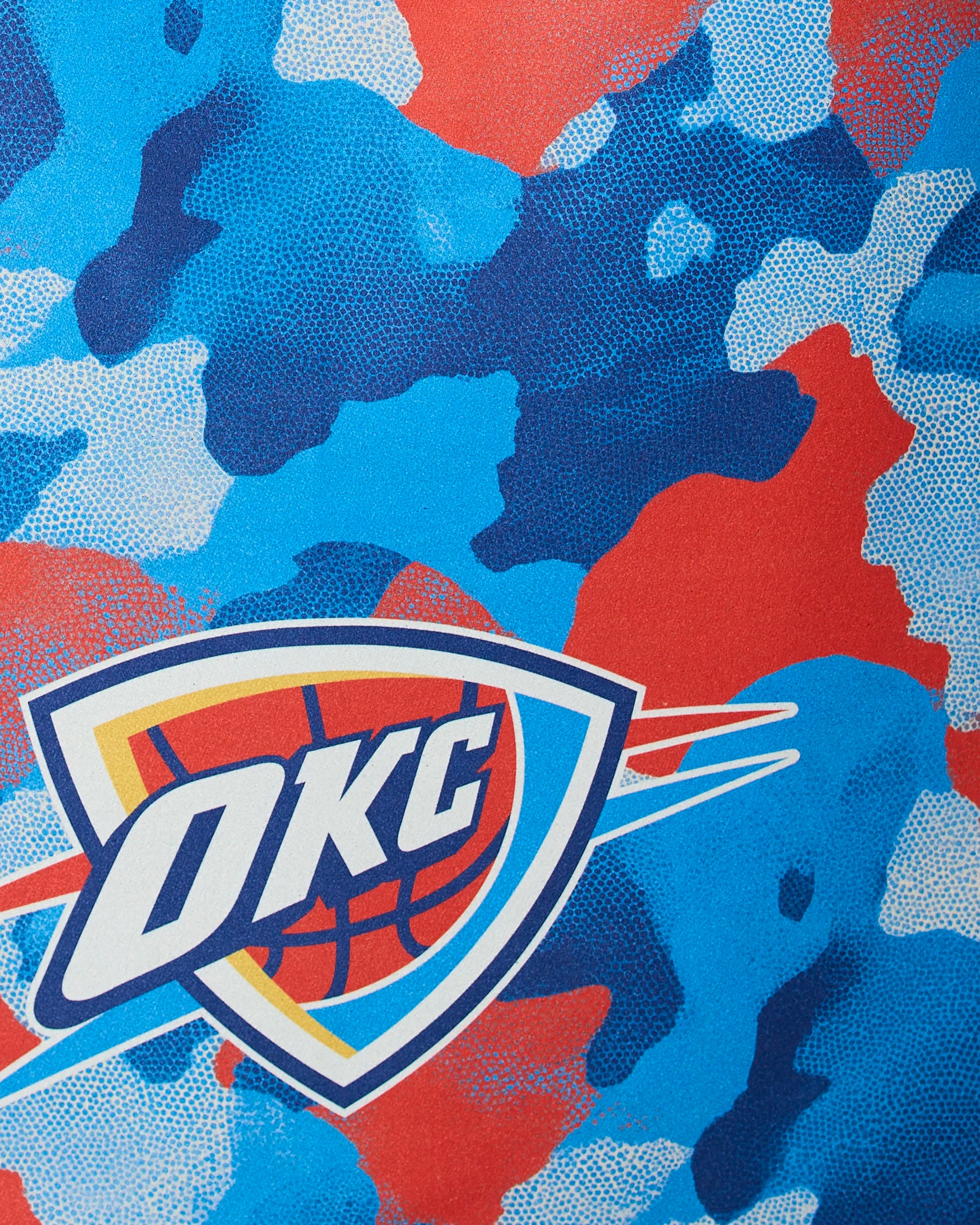 The image displays Geometrys OKC Camo, featuring the Oklahoma City Thunder (OKC) logo with bold letters over a basketball and shield, set against a red, blue, and light blue camouflage background.