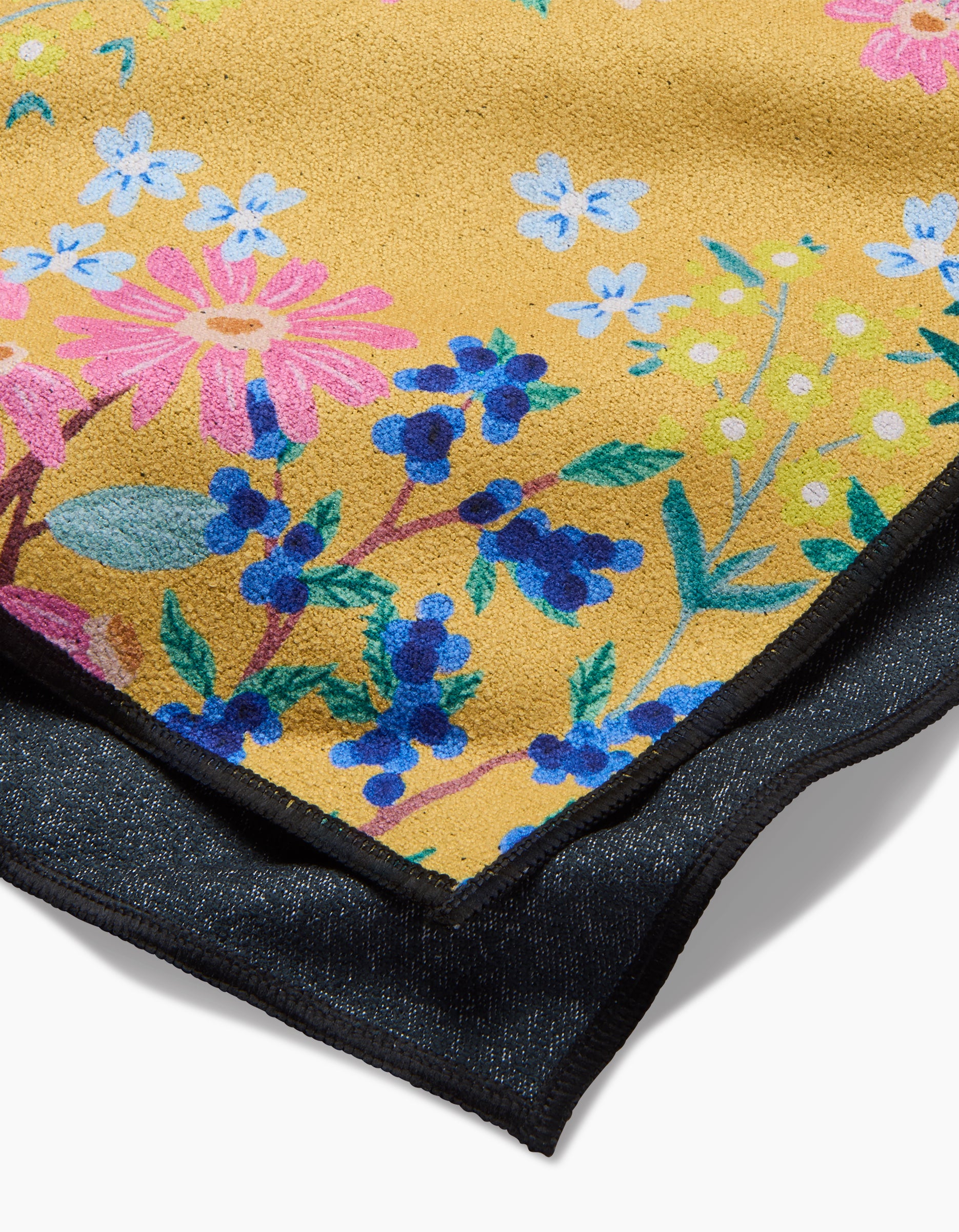 A close-up of Brittany Jepsens Sunny Cherry Blossoms: a yellow recycled fabric with pink, blue, and purple floral patterns, layered over dark textured material.