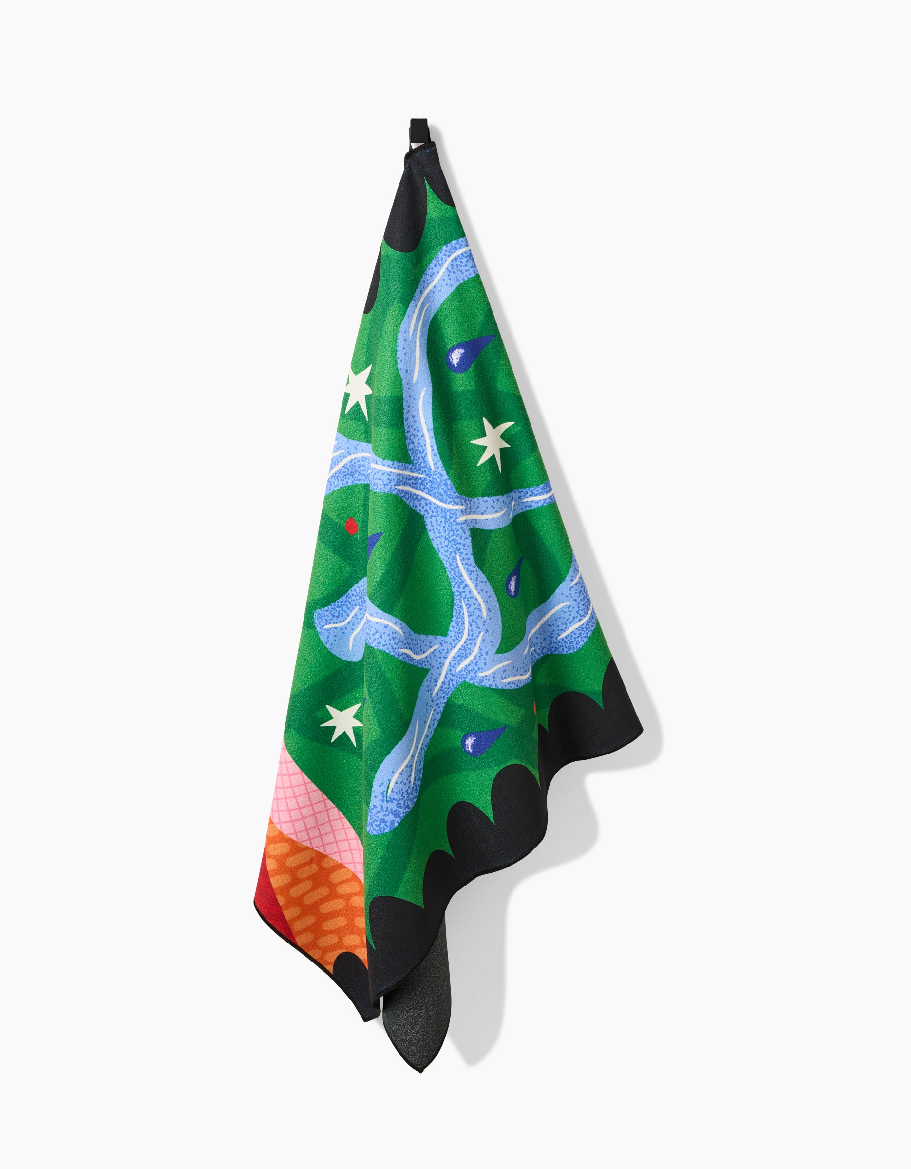 A vibrant Camila Leão Water Micro-loop Beach Towel hangs from a hook, showcasing an abstract design in green, blue, orange, purple, and white. Made from quick-drying recycled materials with stars, wavy lines, and scalloped edges.
