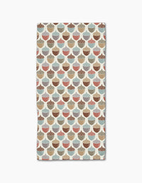 The Acorn Waltz bar towel by Sarah Daugherty is rectangular, ultra-absorbent, and made from recycled materials. It features a repeating acorn pattern in brown, beige, blue, and red on a light background.