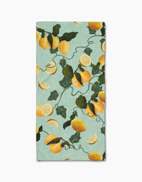 The Pascale Dilger Amalfi Lemons bar towel features a vibrant pattern of whole lemons, lemon slices, and green leaves on light blue, crafted for ultra-absorbency.