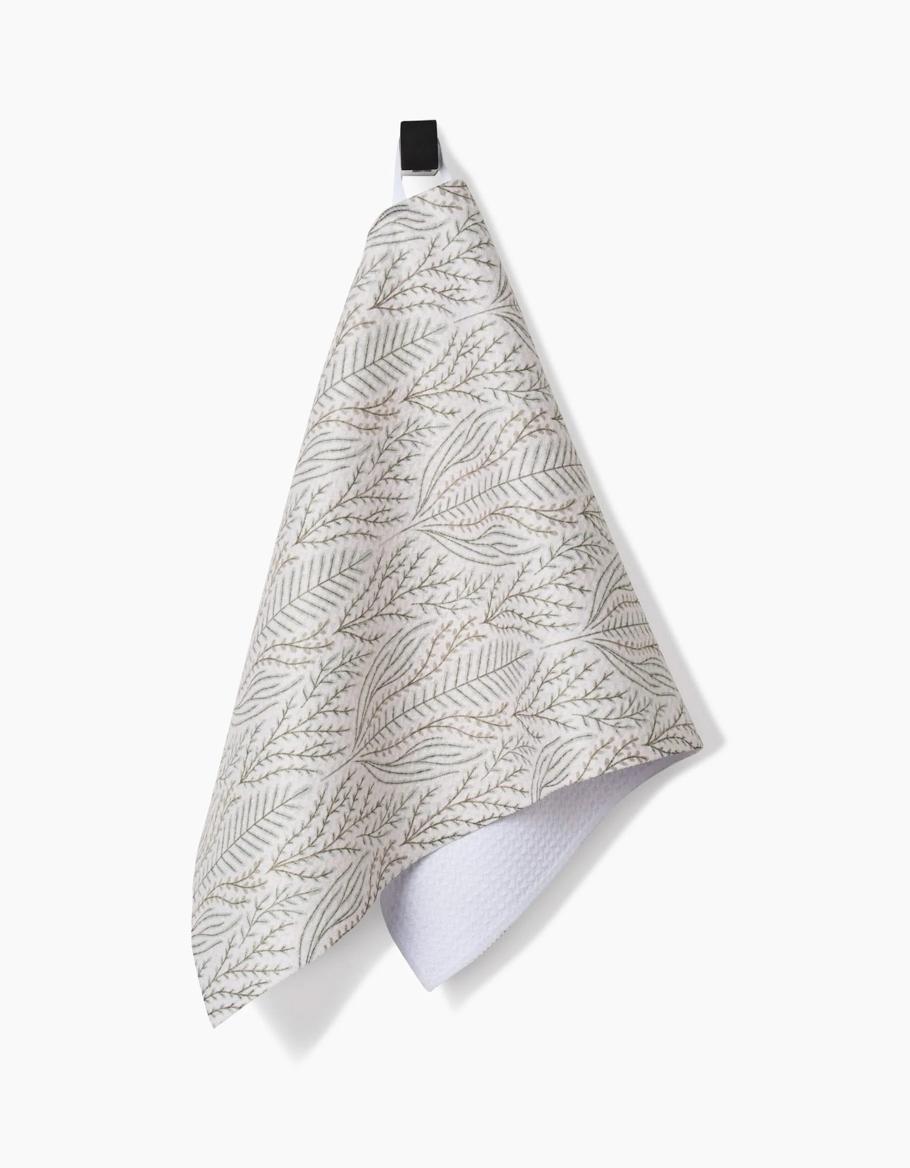 The Amy MacCready Amberlin Bar Towel features a gray leafy pattern and black loop, hangs against a white background. Ultra-absorbent with a folded corner showing its textured underside, it combines stylish design with practical function.