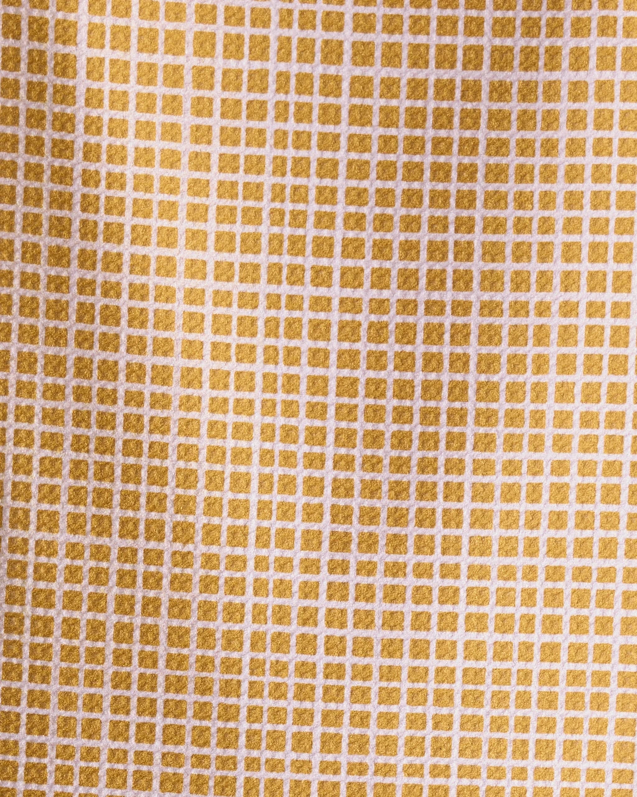 Close-up of the Amberline towel by Geometry, featuring an ultra-absorbent texture and a yellow and white grid pattern with small, evenly spaced squares. Lighting highlights its detailed design and depth.