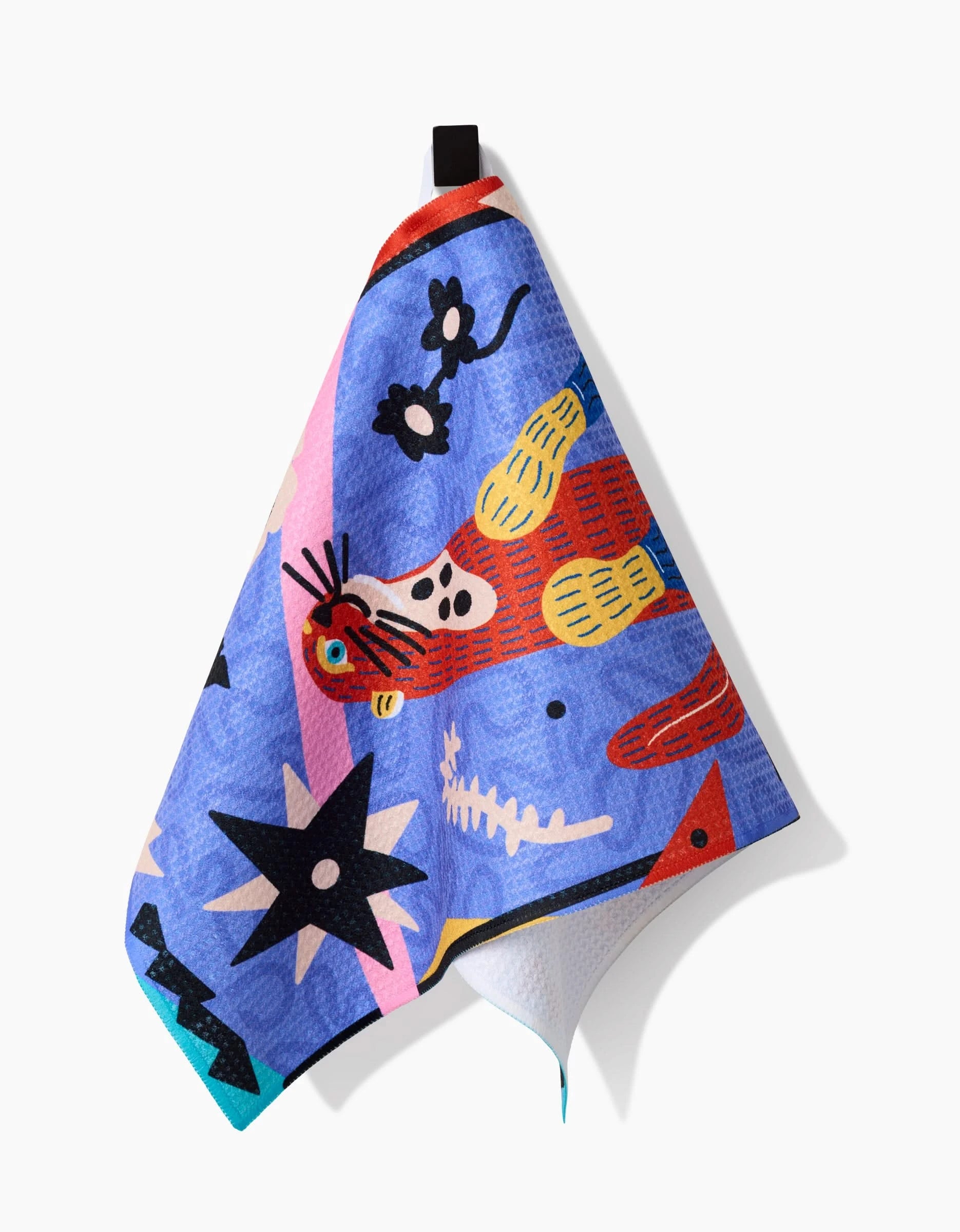 The Ariranha bar towel by Camila Leão features playful abstract designs—red leopard, black stars, and geometric shapes—on ultra-absorbent Geoweave fabric, shown hanging by a black loop against a white background.