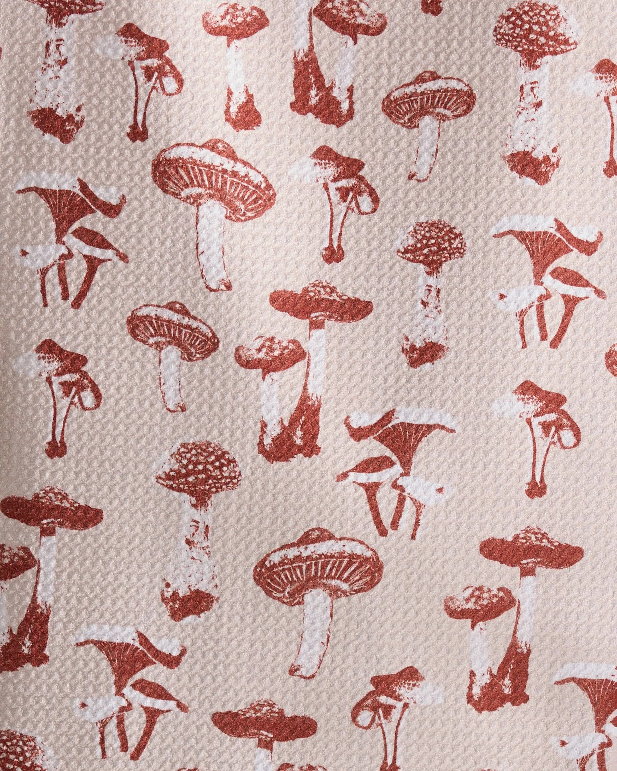 The Autumn Mushrooms towel by Geometry features a repeating pattern of brown mushrooms in various shapes and sizes on a light beige background—perfect as an ultra-absorbent or recycled kitchen towel.
