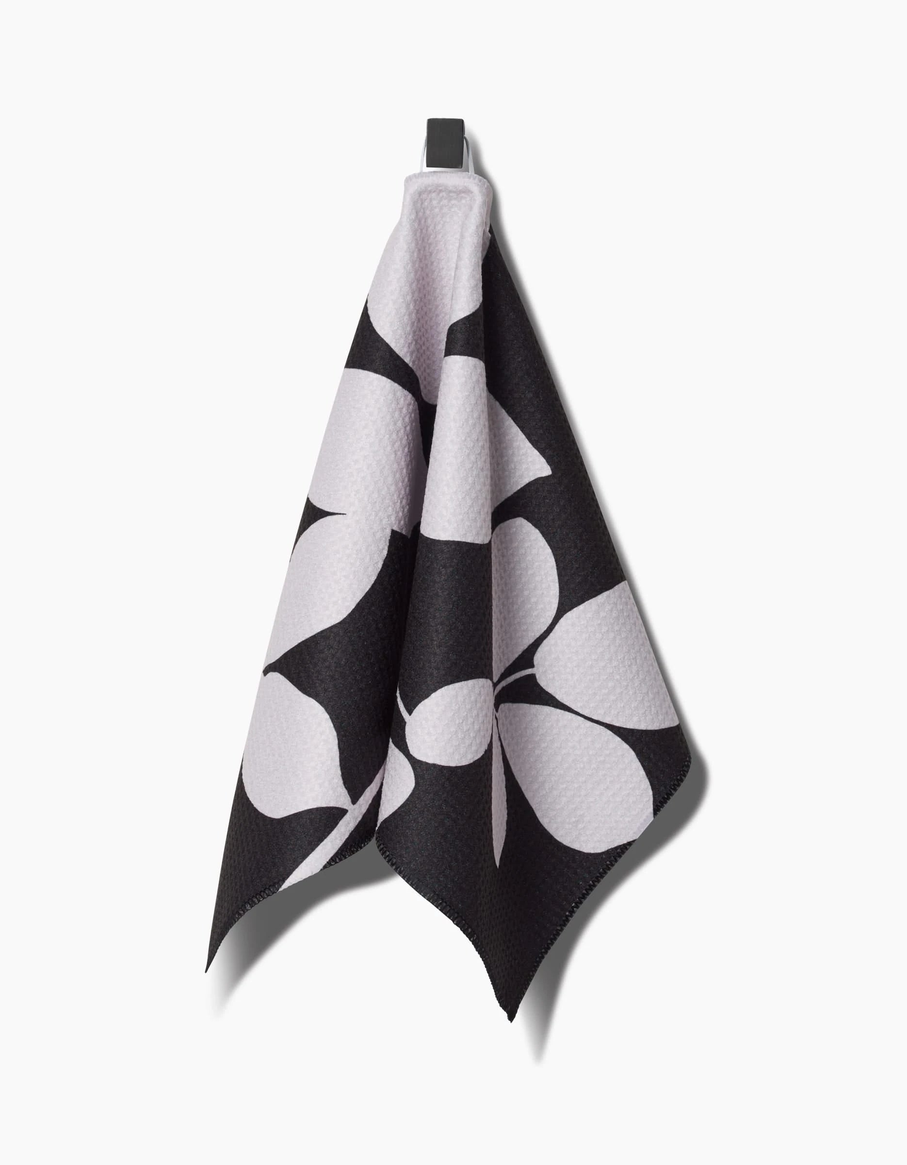 PrintedPlants Blackberry bar towel, crafted from durable Geoweave fabric, features a bold black and white abstract leaf pattern and hangs from a hook against a plain white background.