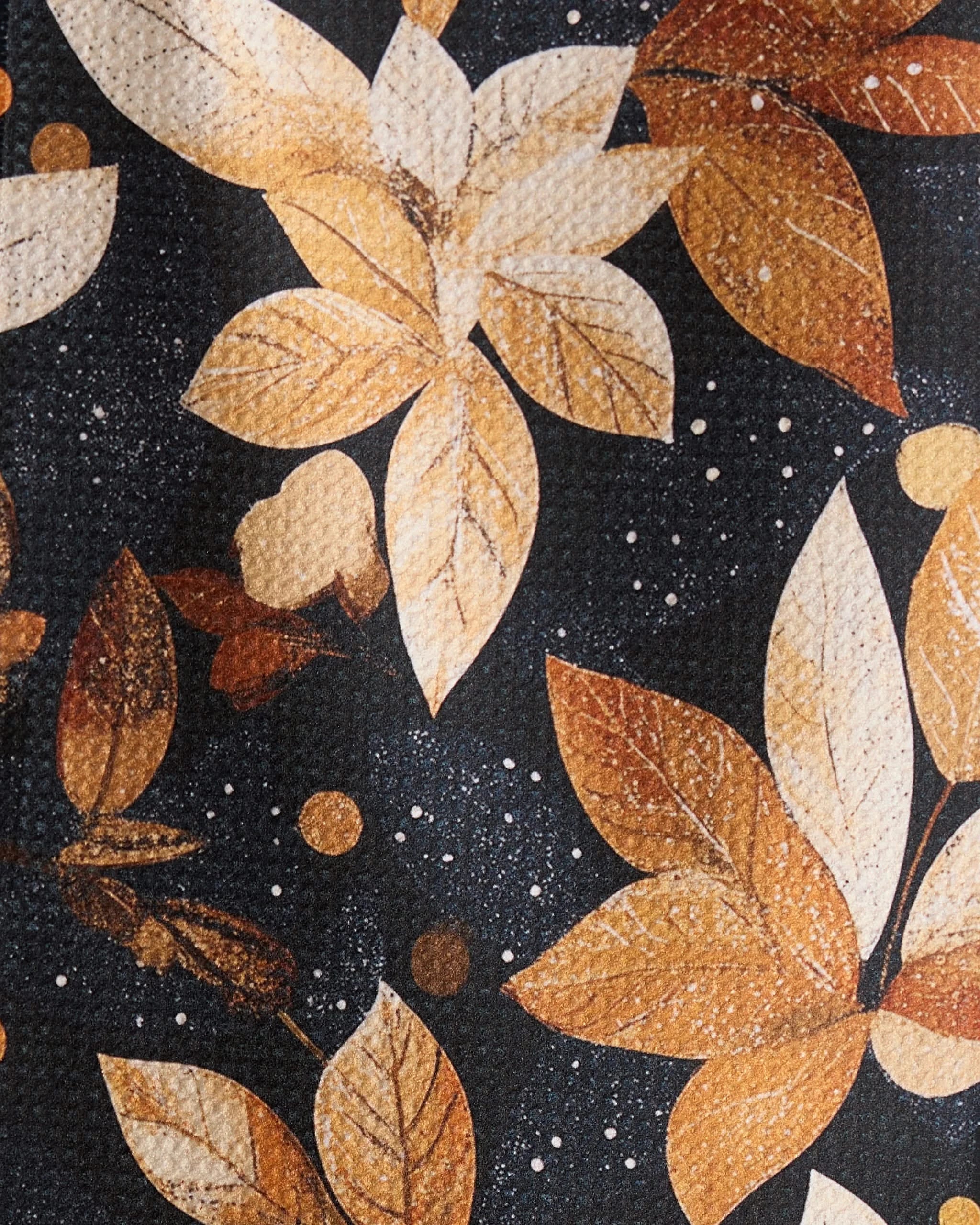 The Geometry Botanical Wonderland bar towel, crafted from recycled materials, showcases an autumn leaf pattern in brown, gold, and cream on a dark background with scattered dots and a textured finish.