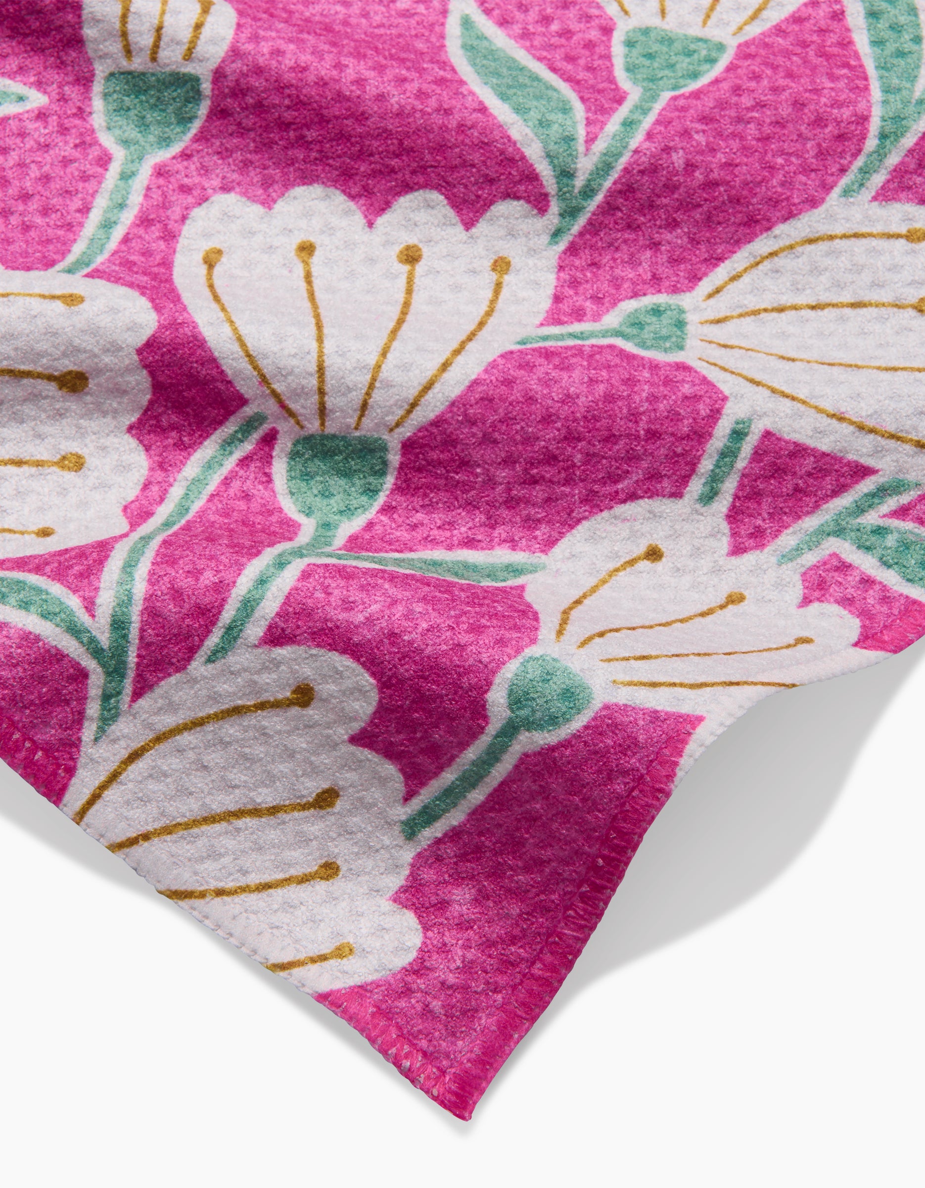 The Clemmie by Amy MacCready is a pink bar towel made from recycled materials, featuring a textured surface and a floral pattern with white flowers, yellow stamens, and green stems.