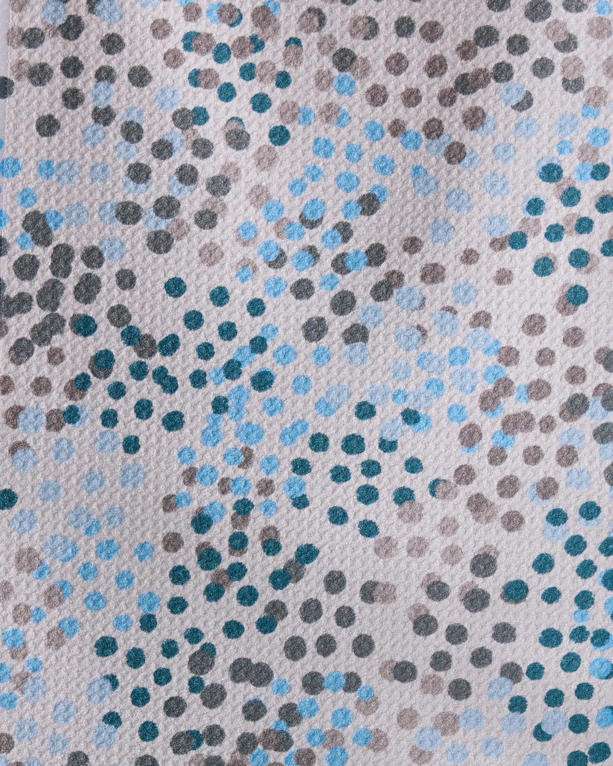 A close-up of Geometry’s Cool Dots recycled kitchen towel, featuring an abstract pattern of irregular blue, black, and gray polka dots on a light background for a modern artistic touch.