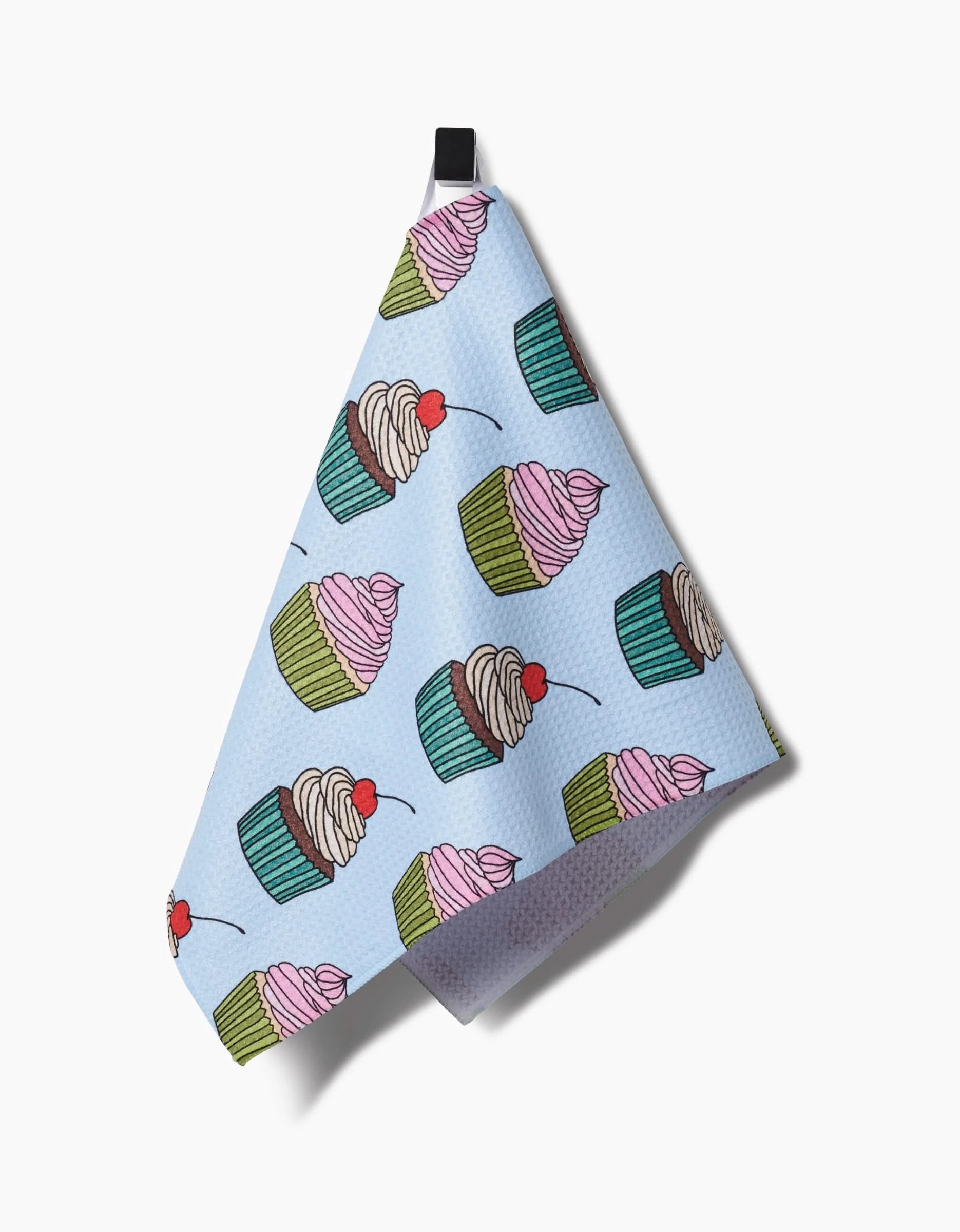 The Amy Droubay Cupcake Love light blue bar towel features a repeating pattern of pink-frosted cupcakes with green liners and red cherries, hangs from a black loop, and is crafted with absorbent Geoweave fabric.
