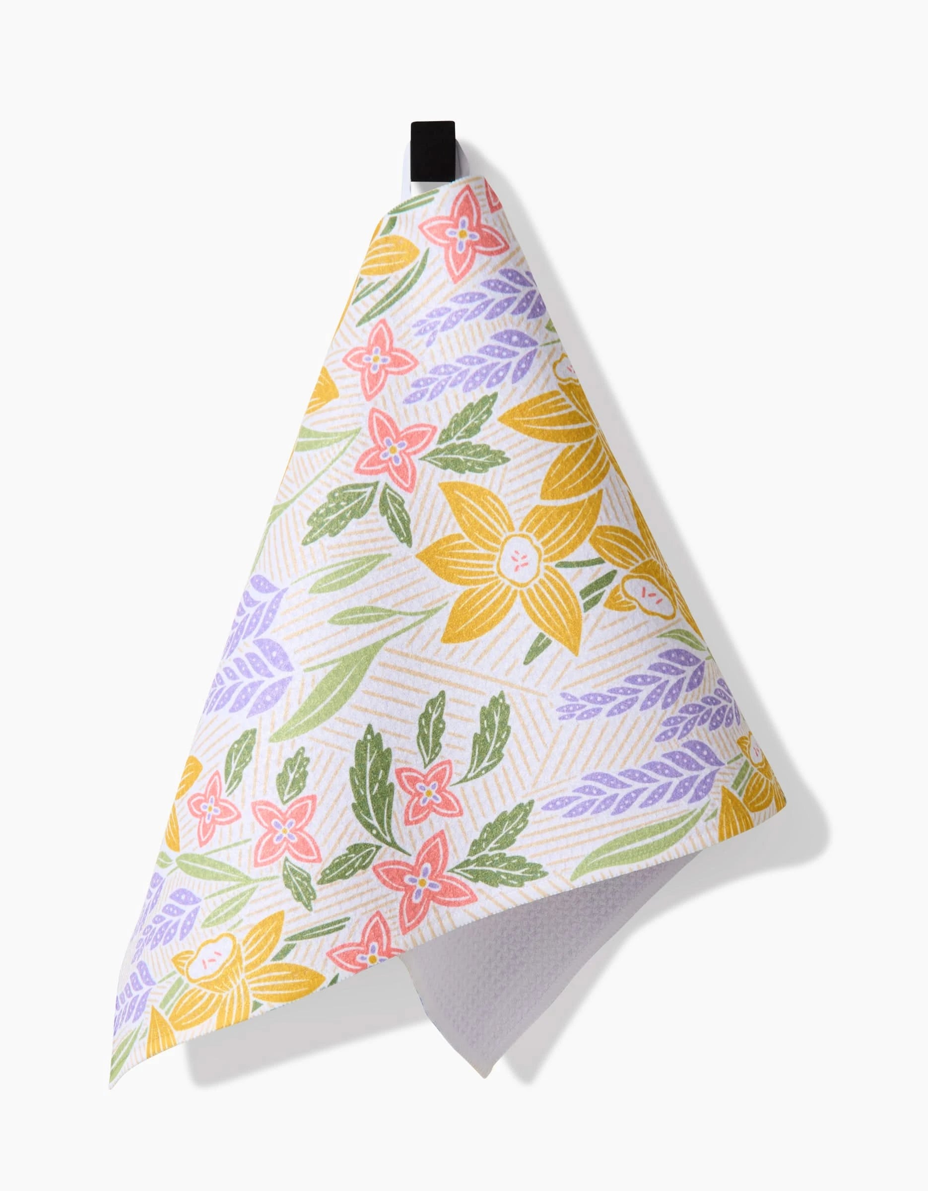 The Daffodil Dreams Bar Towel by Sarah Daugherty, made from Geoweave fabric, features a colorful floral design in yellow, pink, green, and purple, and hangs by a black loop against a plain white background.
