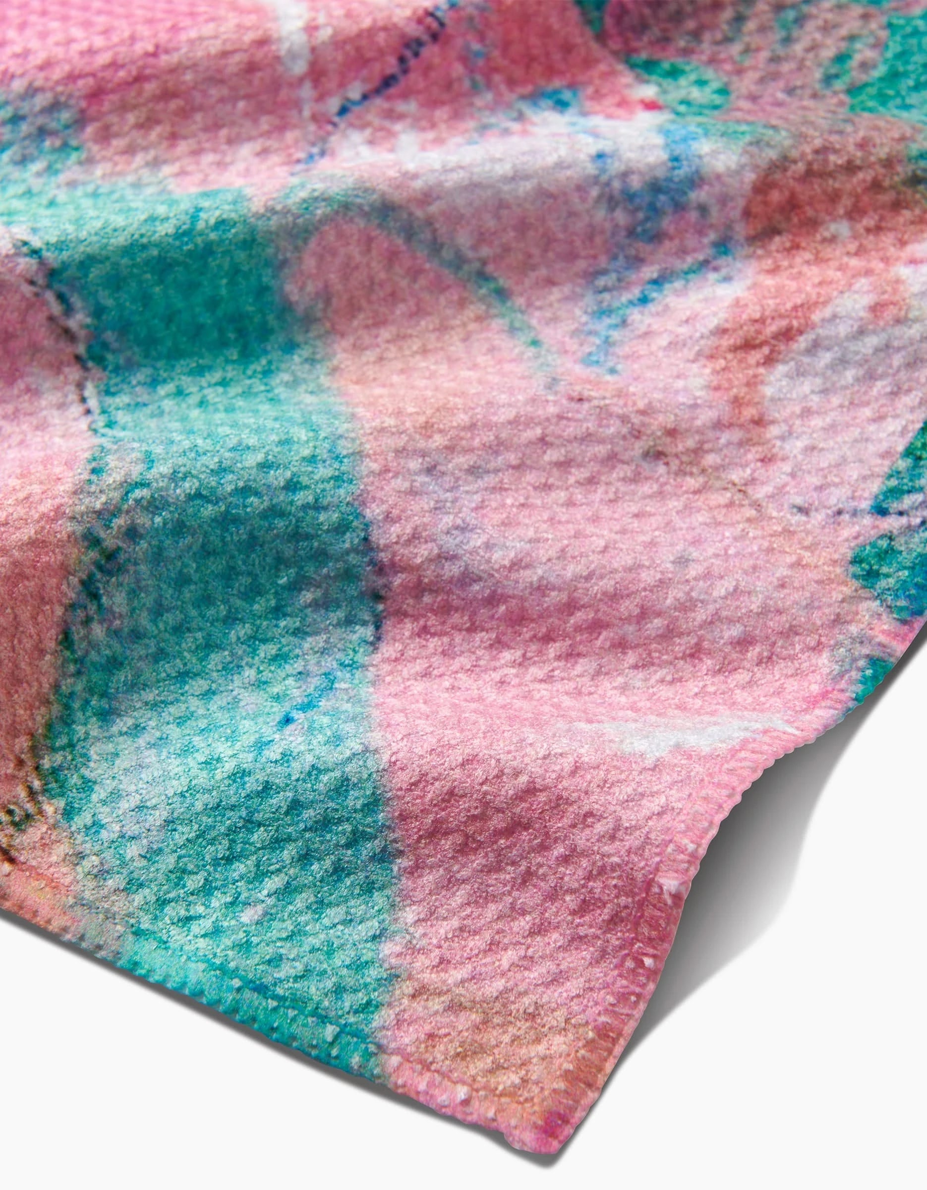 A close-up of the Daughter bar towel by Sarah Holden shows Geoweave fabric with a colorful abstract pink, green, and blue pattern, soft wavy folds, and a neatly finished edge.