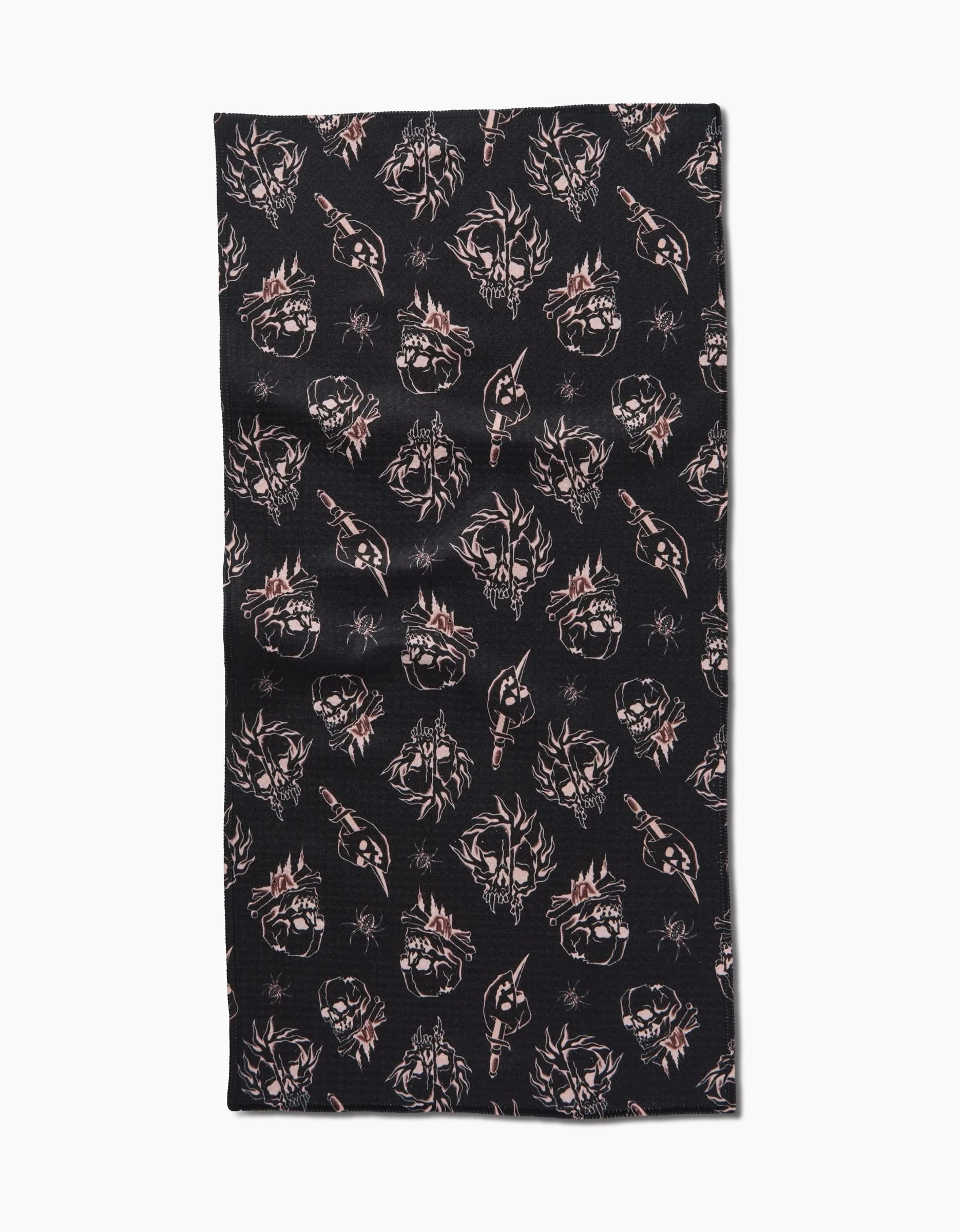 The Cole Strem Fiery Skulls bar towel is black, rectangular, and made from recycled materials, featuring a repeating pattern of light-colored skulls, swords, and wolf heads arranged in rows.