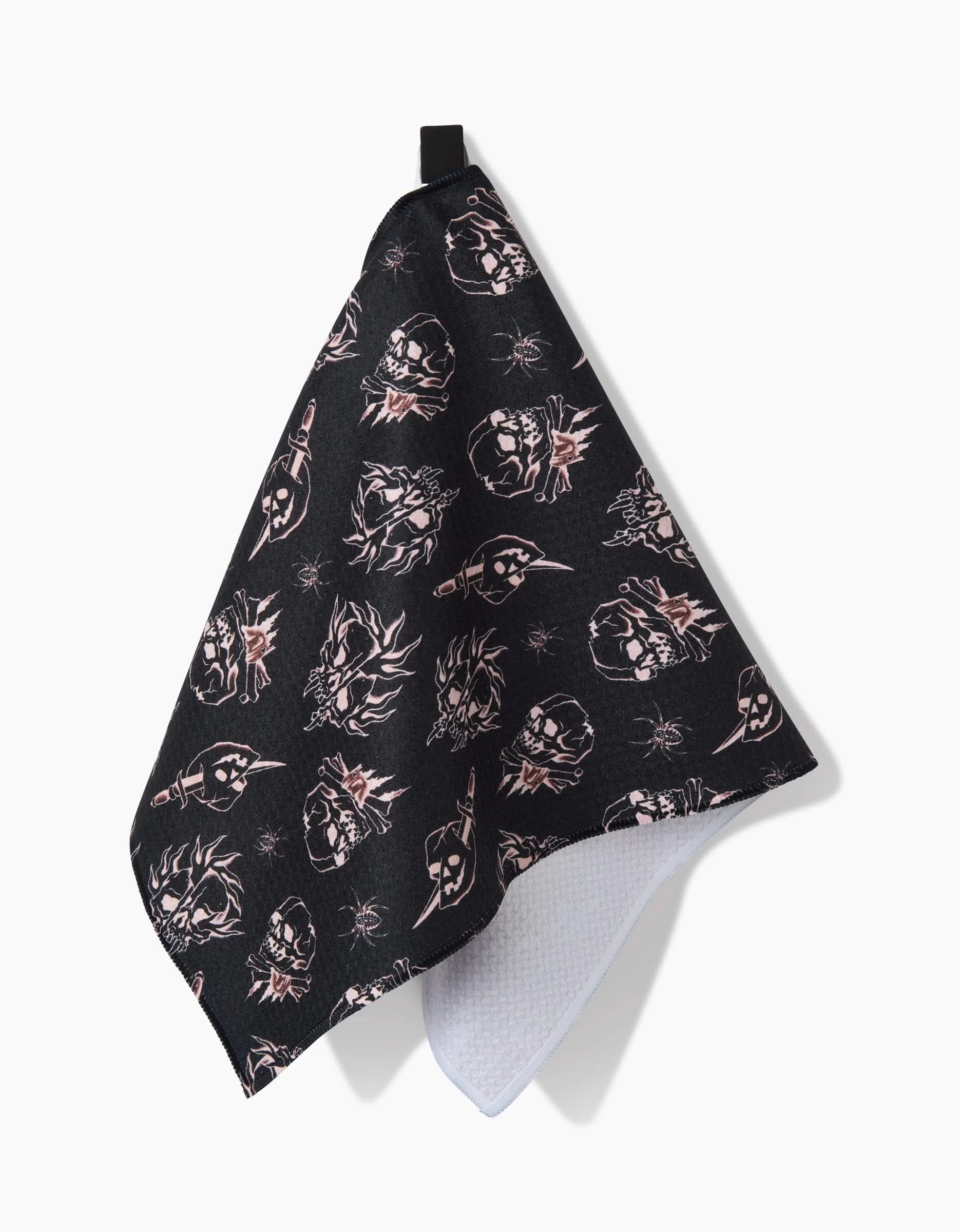 The Cole Strem Fiery Skulls bar towel displays white and pink skull and skeleton designs on black, with a soft white underside, black hanging loop, and ultra-absorbent recycled materials, shown against a white background.