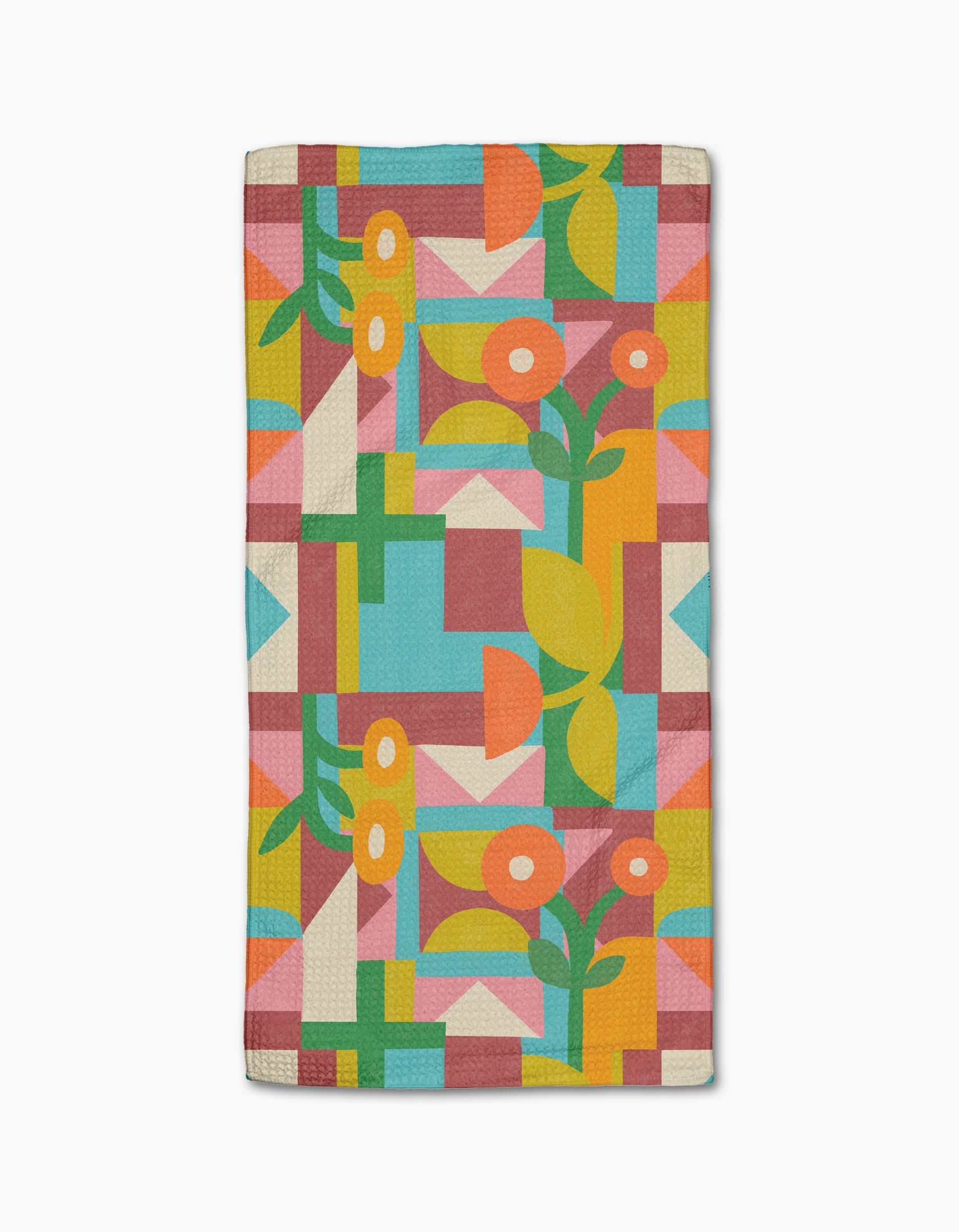The Floral Geometry rug by Lisa Nelson features colorful geometric and stylized floral patterns in orange, yellow, green, blue, pink, and white tones. Made from recycled materials, it showcases abstract shapes with flowers and leaves throughout.