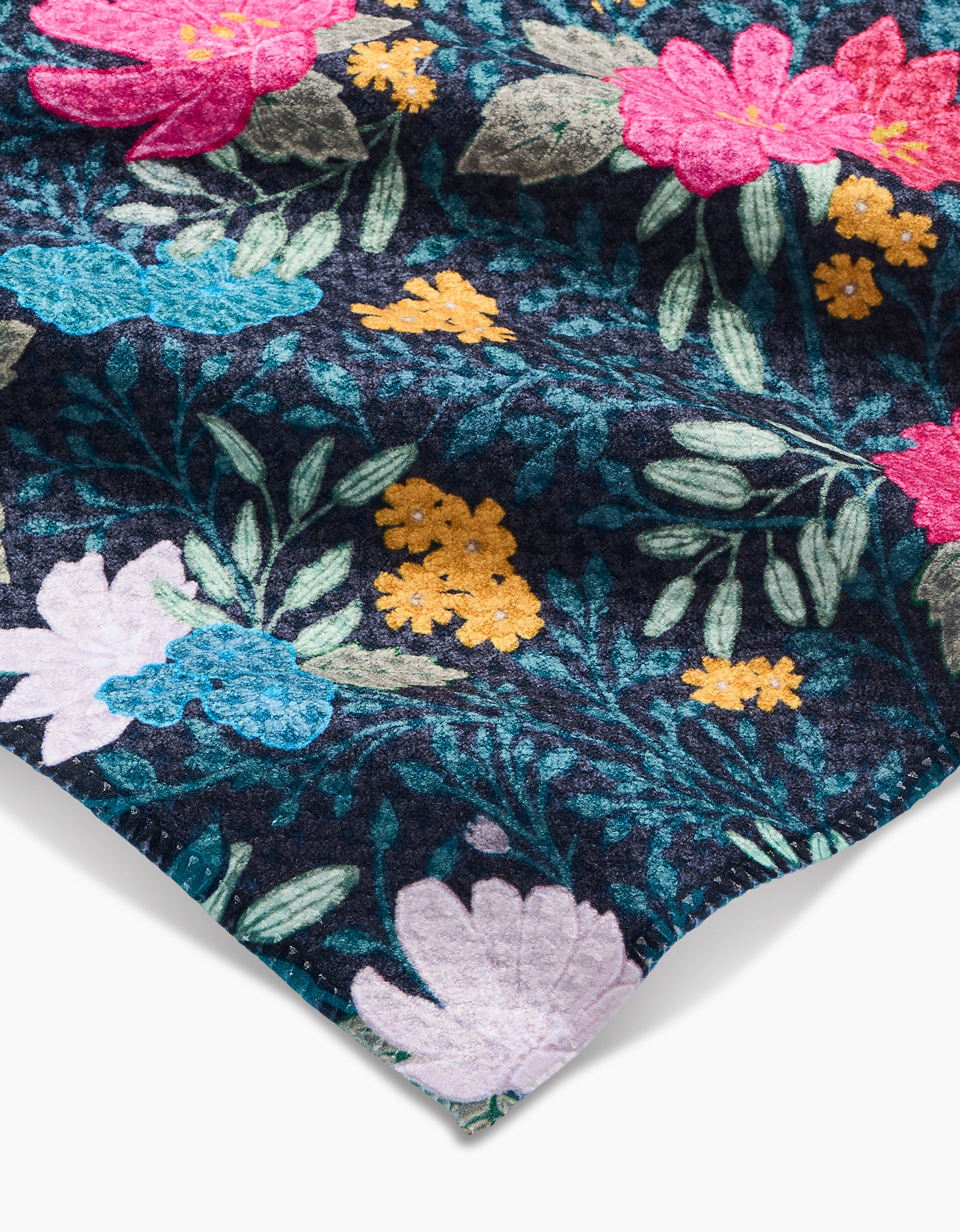 A close-up of the Flower Bouquets Bar Towel by Katie OShea, featuring dark Geoweave fabric with a vibrant floral pattern in pink, blue, white, and yellow flowers with green leaves. The towel’s edge appears in the lower corner.