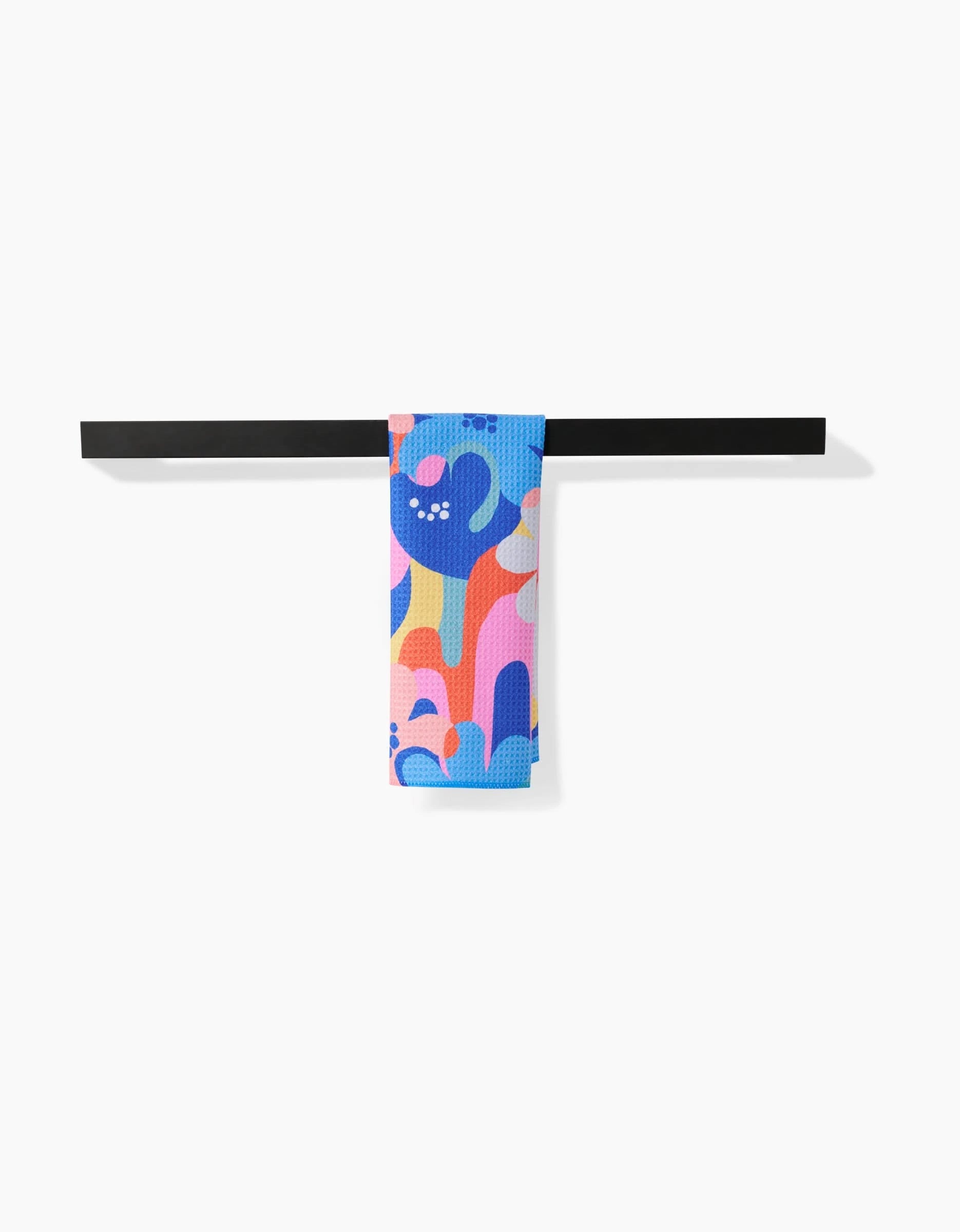 The Flower Powers Bar Towel by Masha Volnova features abstract blue, pink, orange, and purple shapes on soft Geoweave fabric. It hangs neatly over a black rod against a white background, offering superior absorbency.