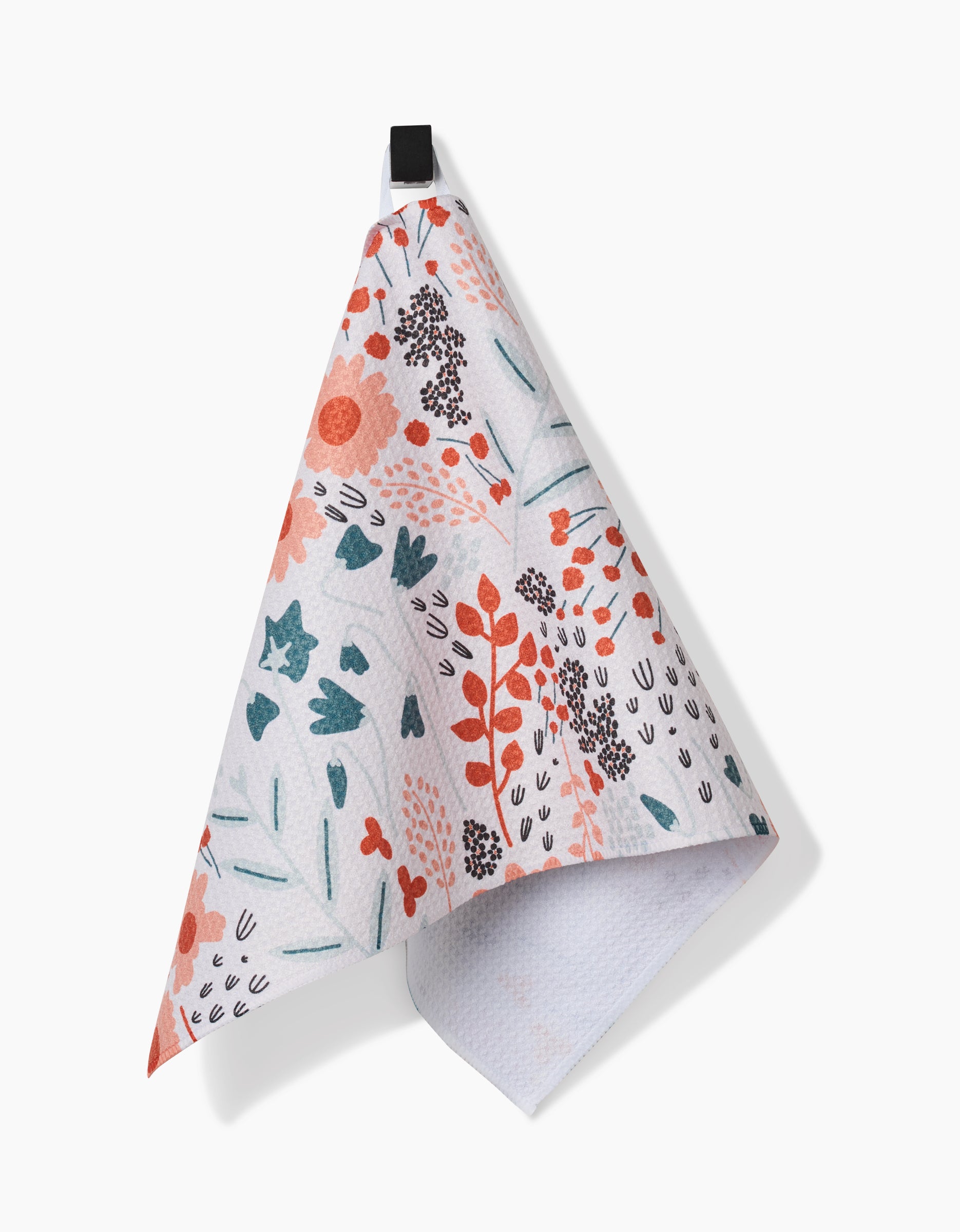 The Forest Foliage bar towel by Coit Creative, made from post-consumer recycled materials, displays a vibrant floral design in red, pink, teal, and green and hangs from a black loop against a plain white background.