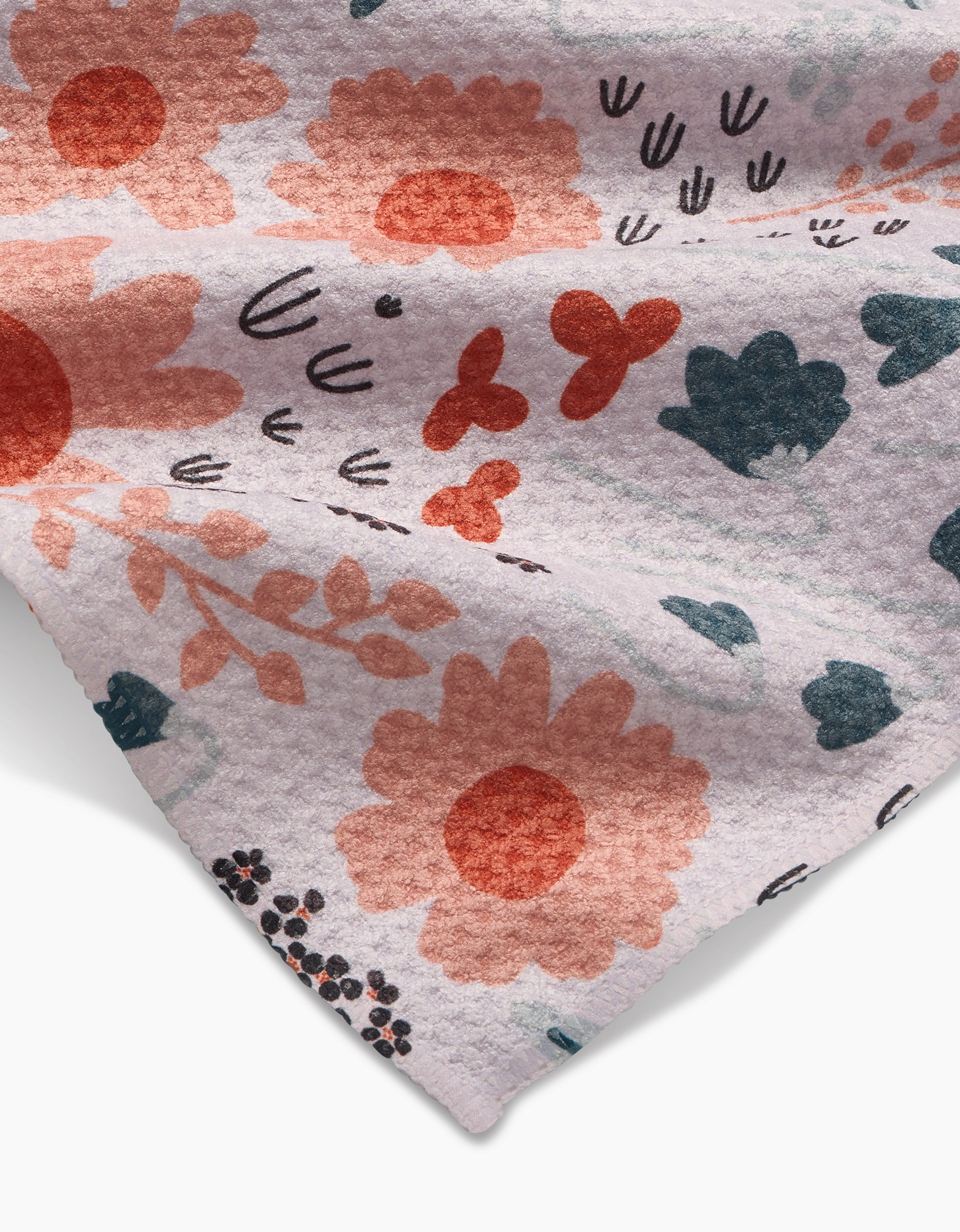 A close-up of Coit Creatives Forest Foliage Bar Towel, crafted from textured Geoweave fabric and featuring a floral and botanical print in orange, coral, navy, and black on a light background.