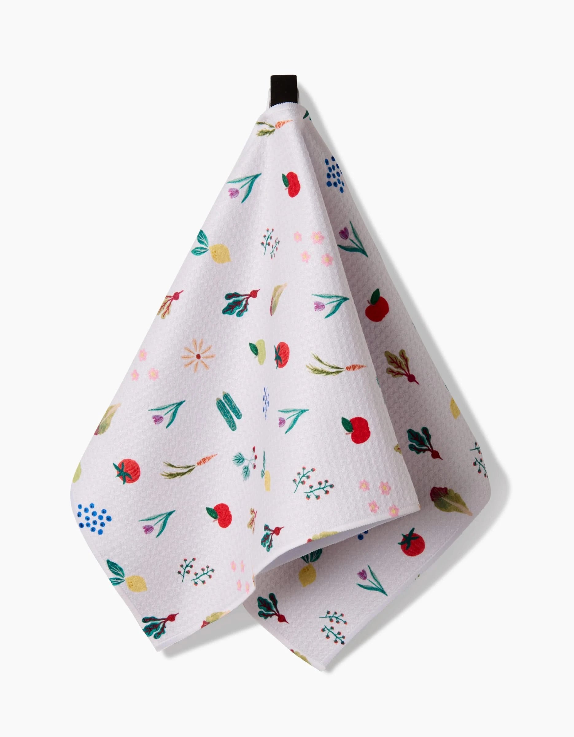 The Fresh Produce towel by Brittany Jepsen, made from ultra-absorbent Geoweave fabric, features a colorful fruit, leaf, and flower pattern on white and hangs from a black loop against a plain background.