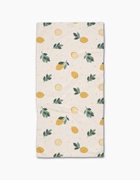 The Freshly Picked Bar Towel by Sara Mari is a rectangular beige towel with yellow lemons, lemon slices, green leaves, and dots. Made from Geoweave fabric for superior absorbency and durability.