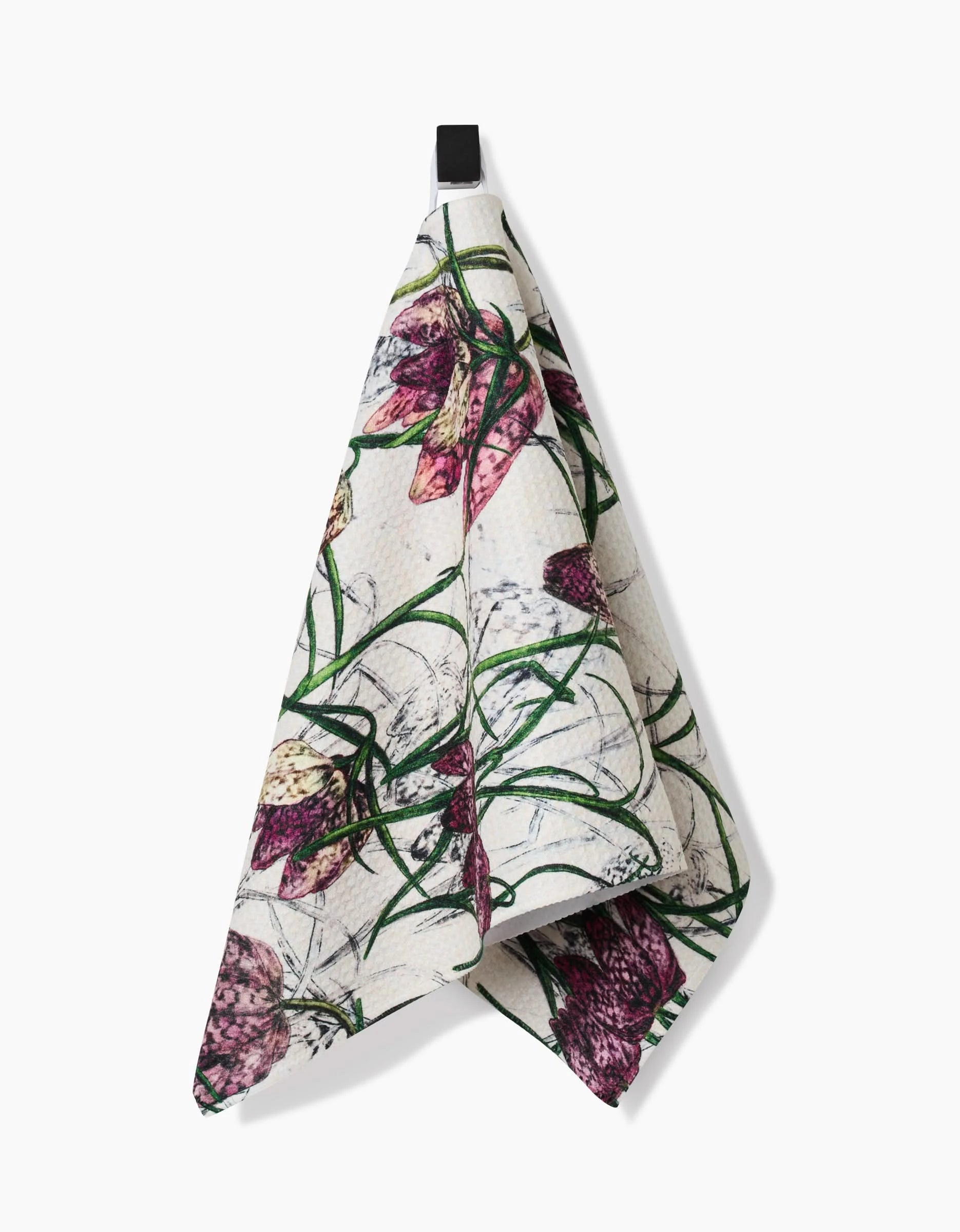 The Pascale Dilger Fritillaria bar towel features a botanical print of purple and pink flowers with green leaves on ultra-absorbent white Geoweave fabric, and hangs from a black loop.