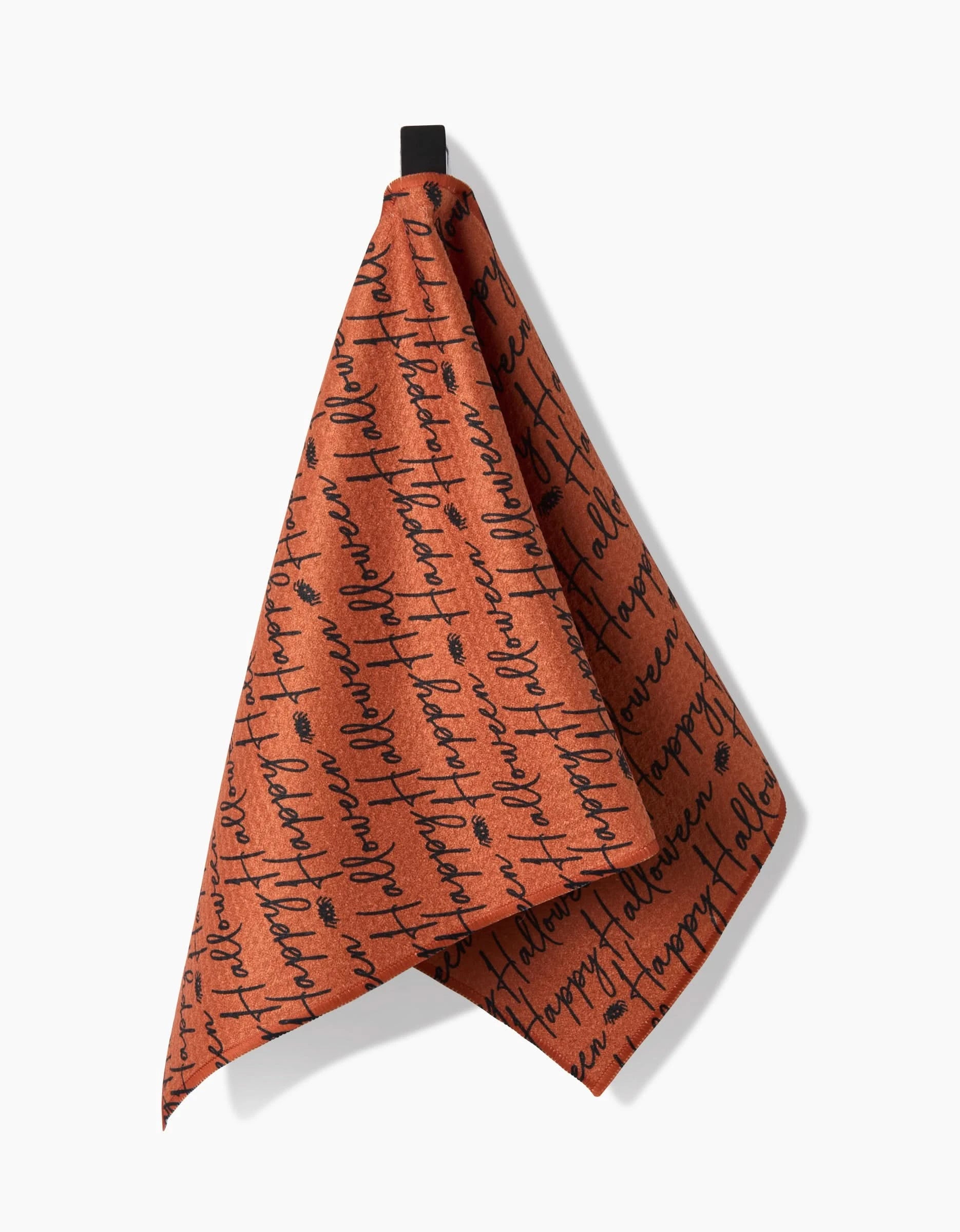 The Geometry Halloween Script Orange towel is ultra-absorbent, rust-colored, and hangs from a black loop with repeated black cursive script printed across its surface.