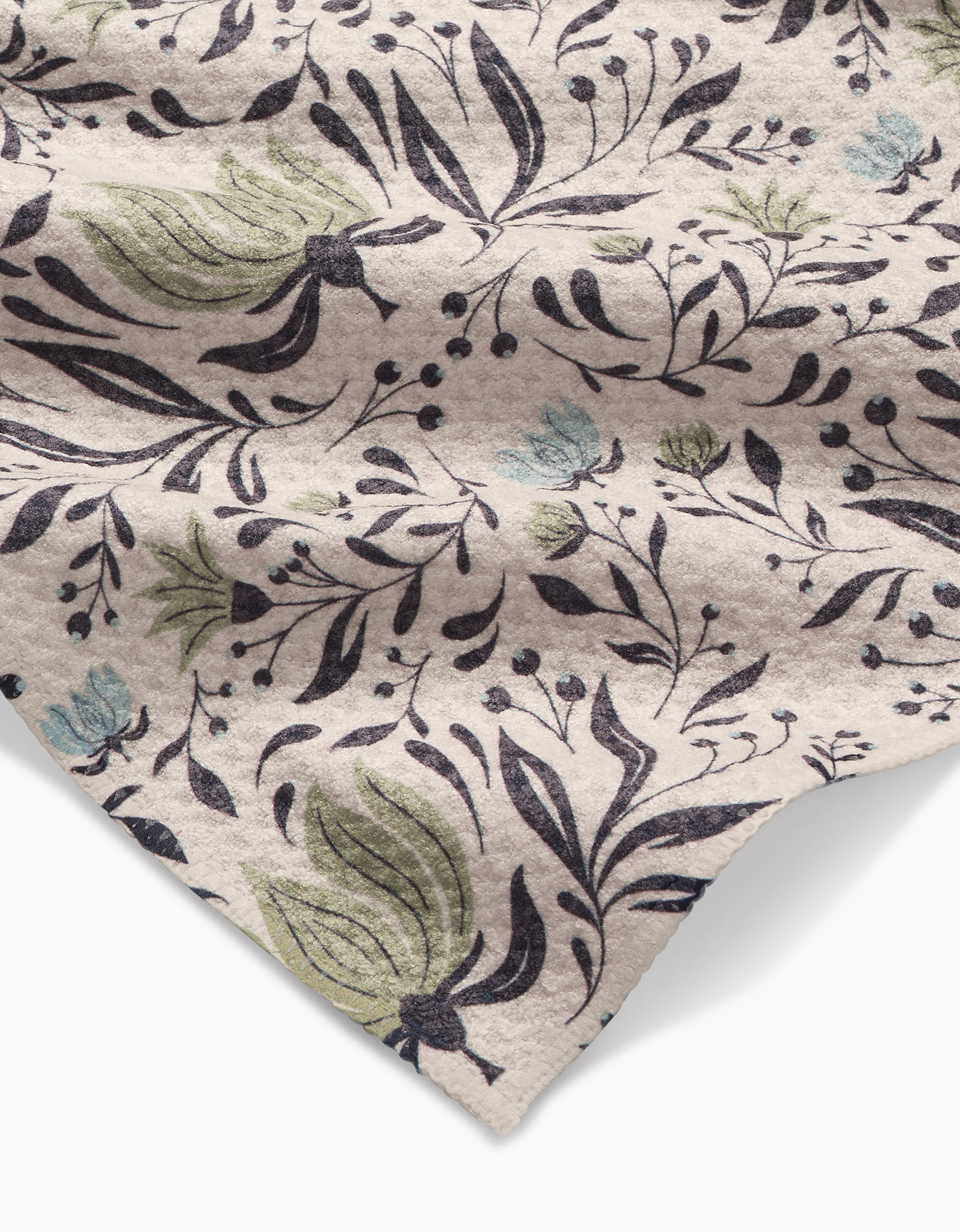 A close-up of the Hello Flowers Bar Towel by Amita Nair, made from ultra-absorbent Geoweave fabric with a floral design in black outlines, green leaves, and blue flowers. Its cream color and textured finish are clearly visible.