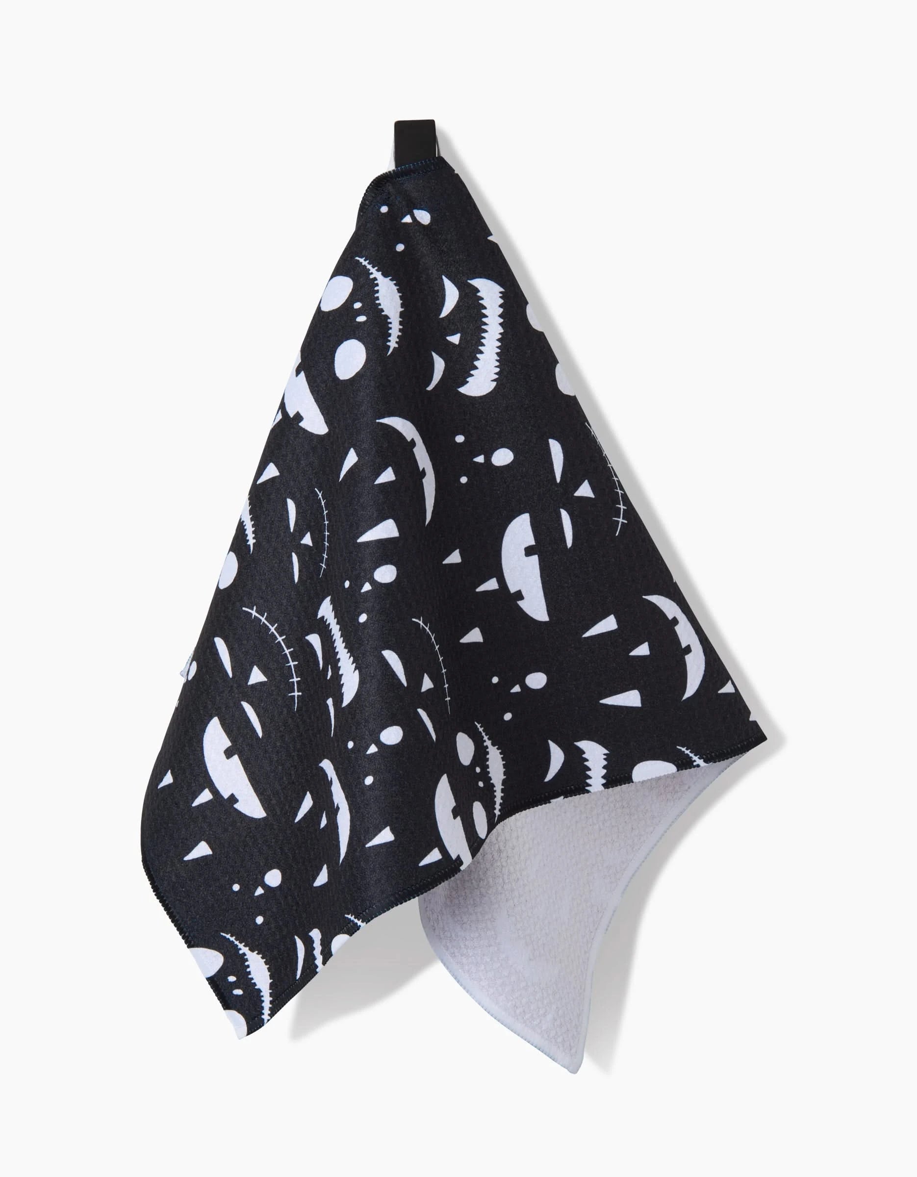 The Danelys Sidron Jack O Lantern Jamboree Black towel features ultra-absorbent black fabric with white Halloween pumpkin faces and a black hanging loop—ideal as a festive bar towel.