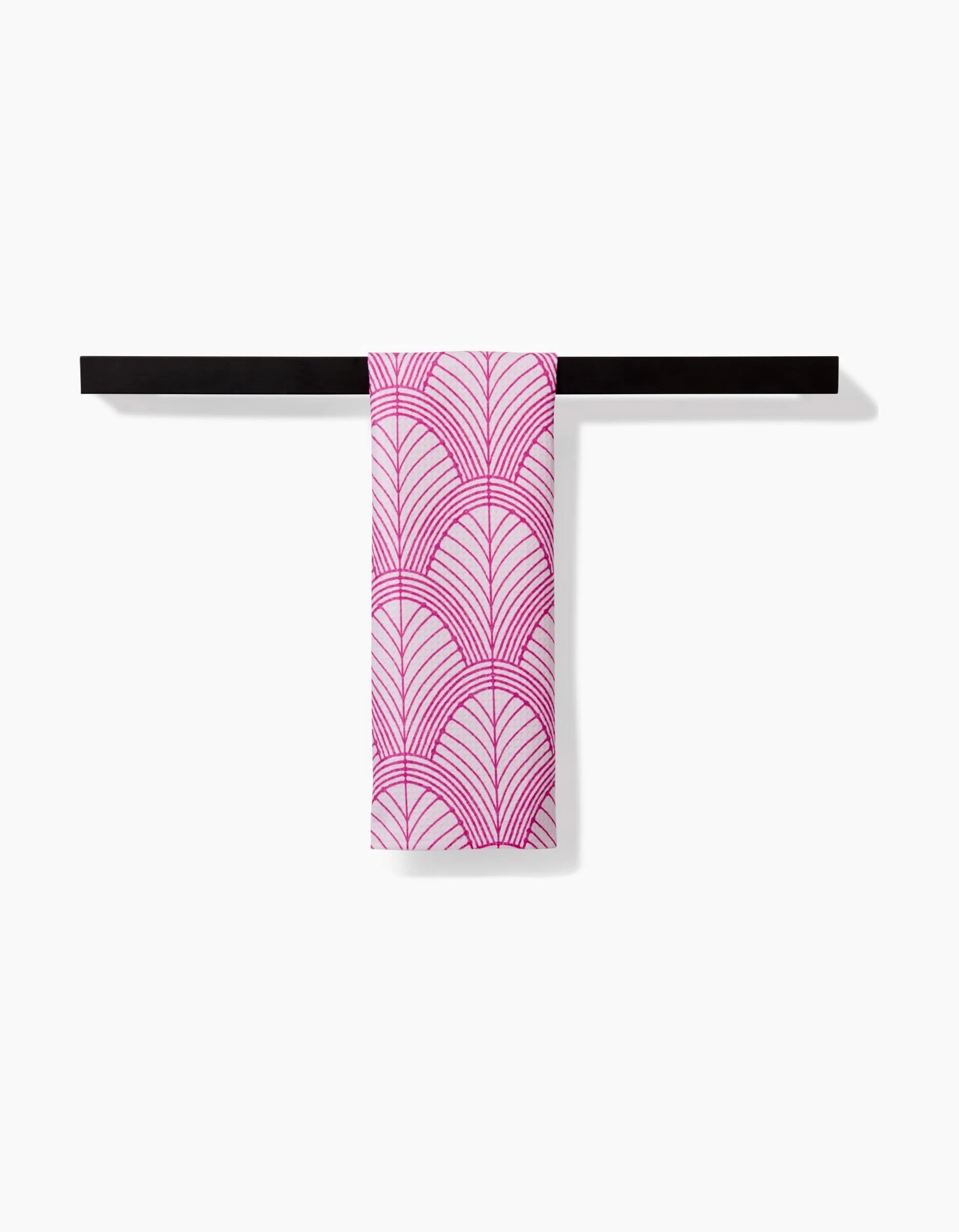 The Jaskin bar towel by Amy MacCready, featuring a pink geometric fan pattern in Geoweave fabric, hangs neatly on a sleek black towel bar against a plain white background.