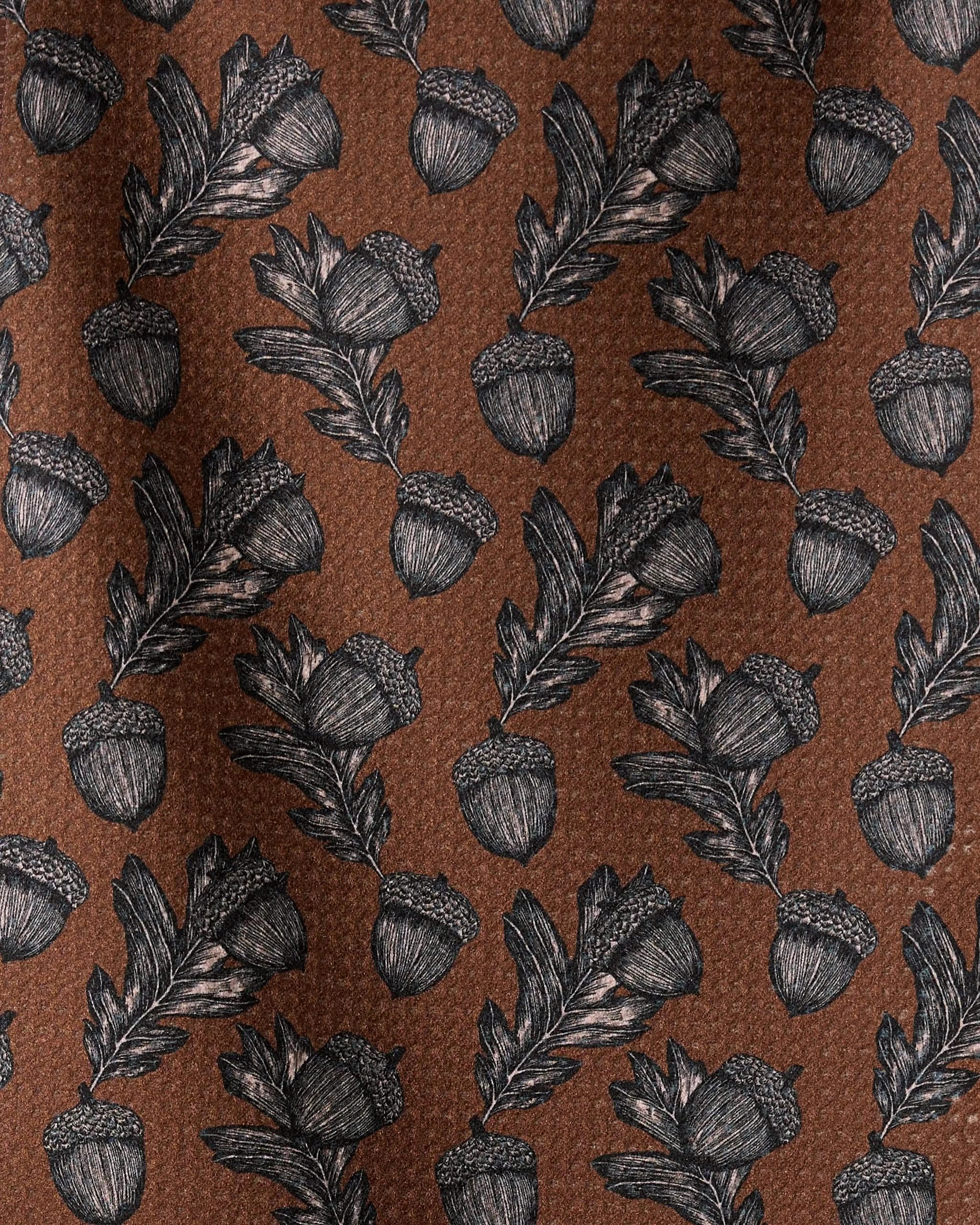 The Geometry Kindred bar towel features a brown fabric with black and white acorn and oak leaf illustrations in a repeating design, and is crafted from recycled materials.