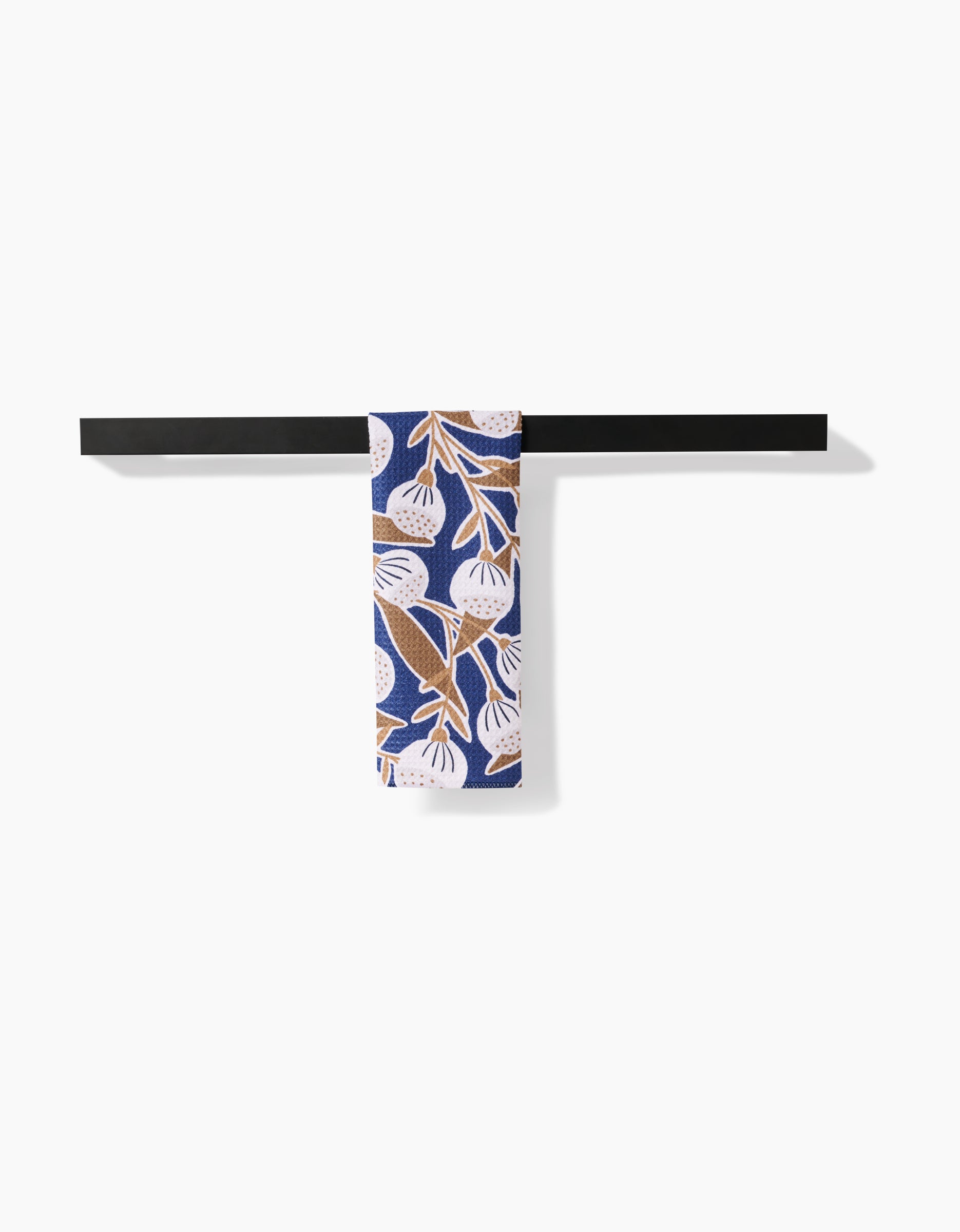 The Leslie towel holder by Amy MacCready features a black horizontal bar and includes an ultra-absorbent towel with a blue background and white and brown botanical leaves, displayed against a plain white background.