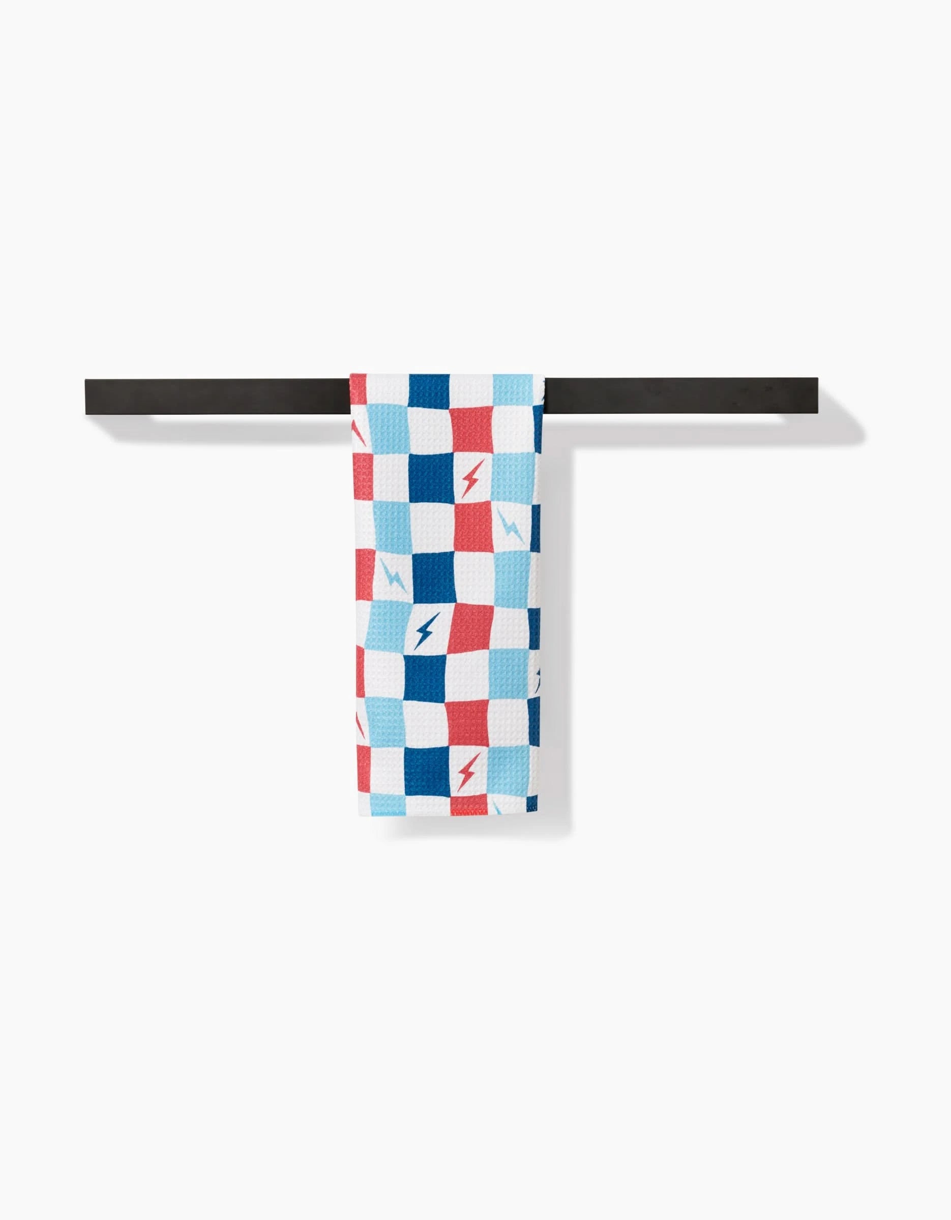 The Lightening Bolt Chess Bar Towel by Hufton Studio features a red, blue, and white checkered pattern with blue and red lightning bolts. Made from Geoweave fabric, it is draped over a black towel bar against a white background.